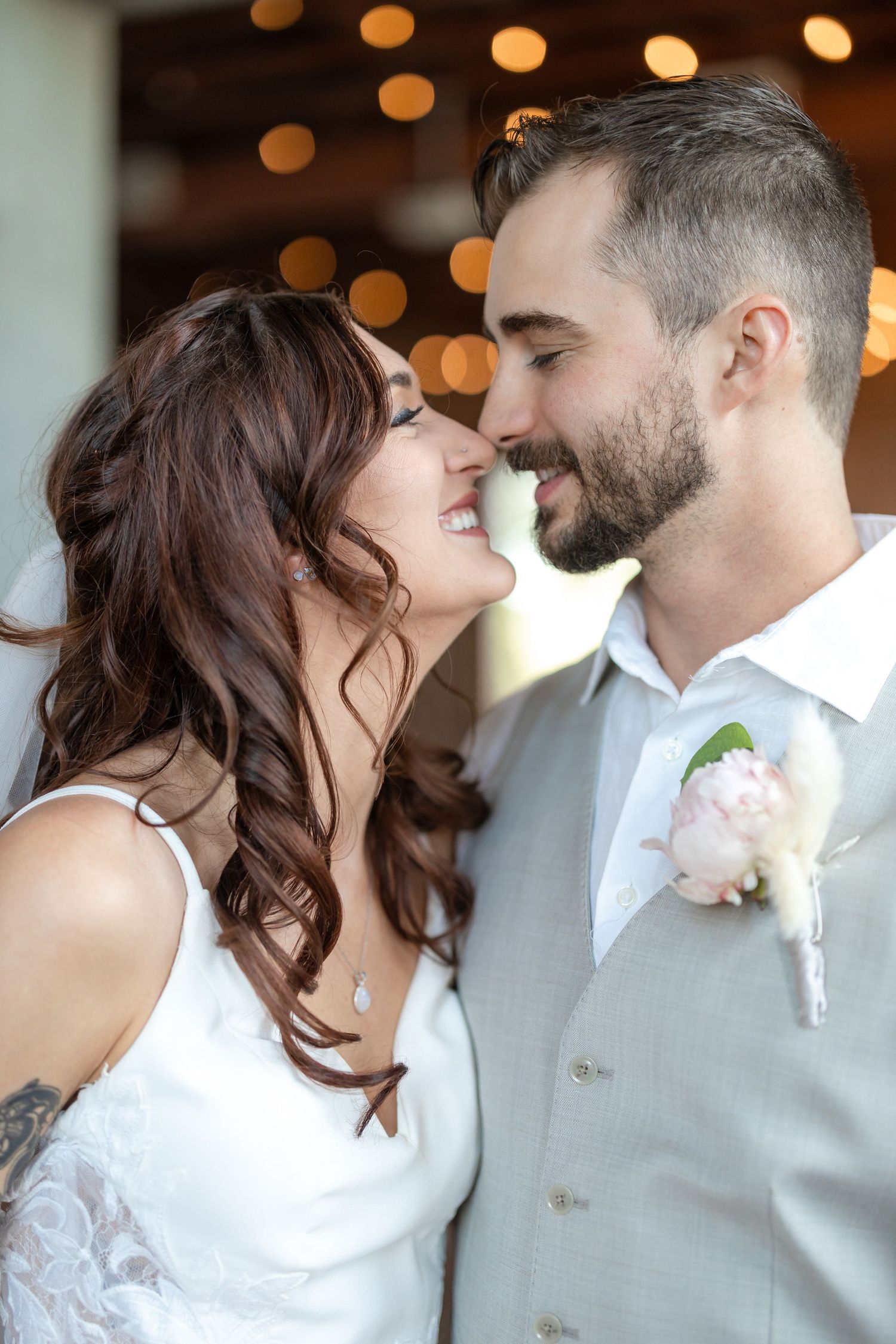 Joyful wedding portrait with bokeh lights and exposed brick backdrop.