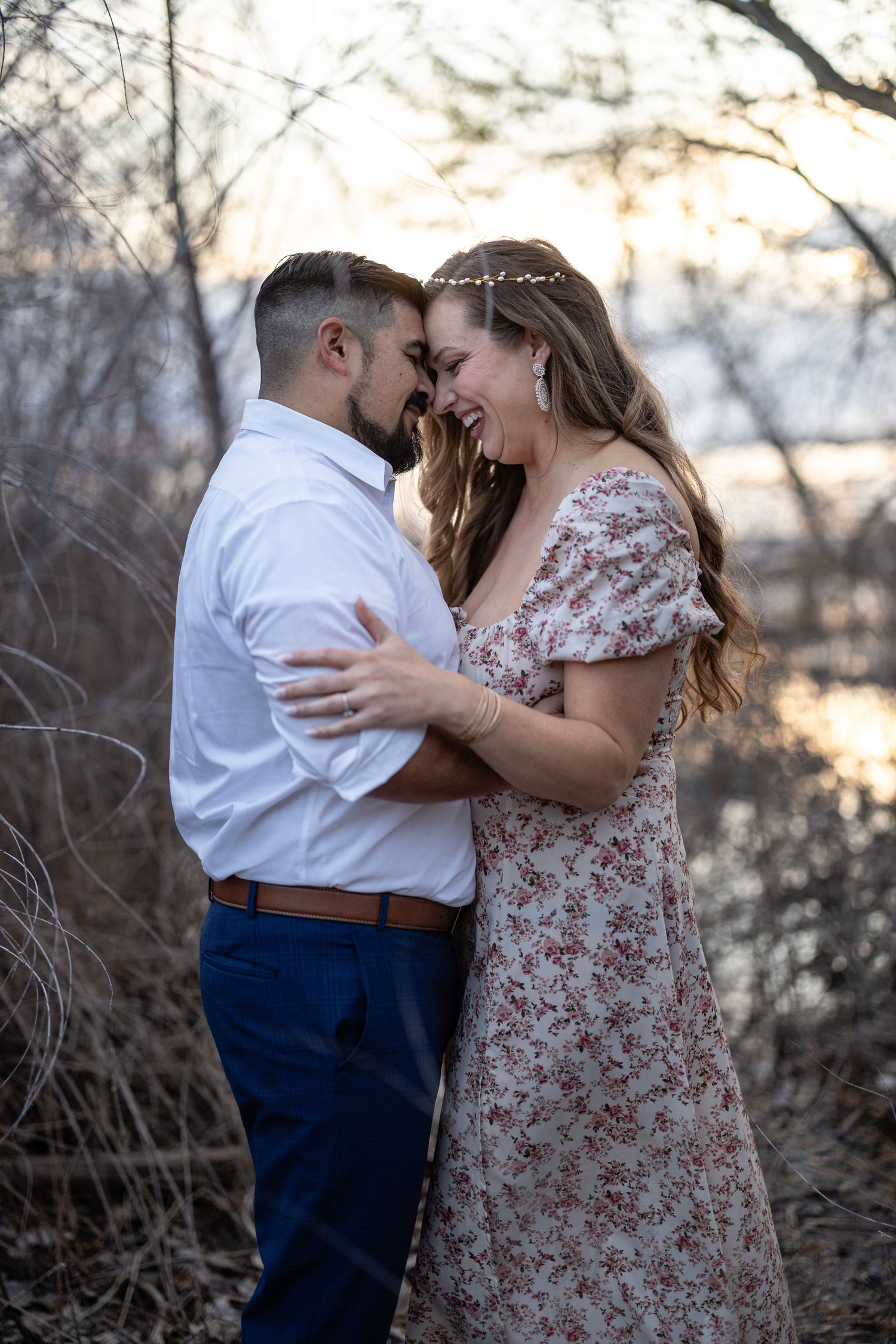 A couple shares a romantic moment at sunset by the water's edge.