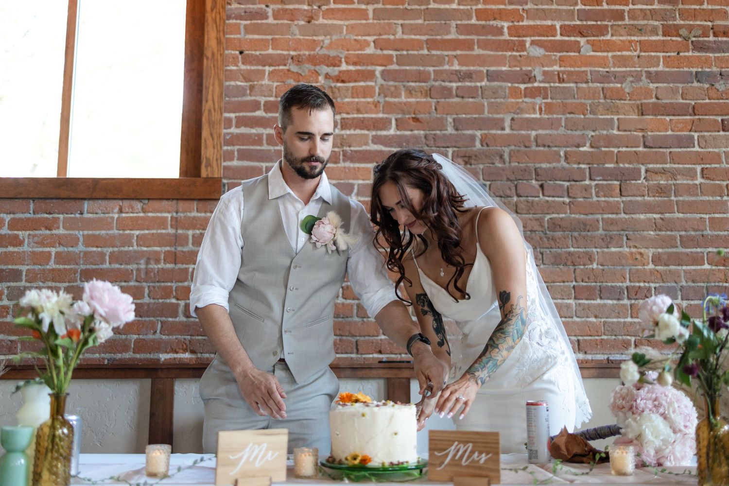 Newlyweds cut their wedding cake together at rustic brick venue.