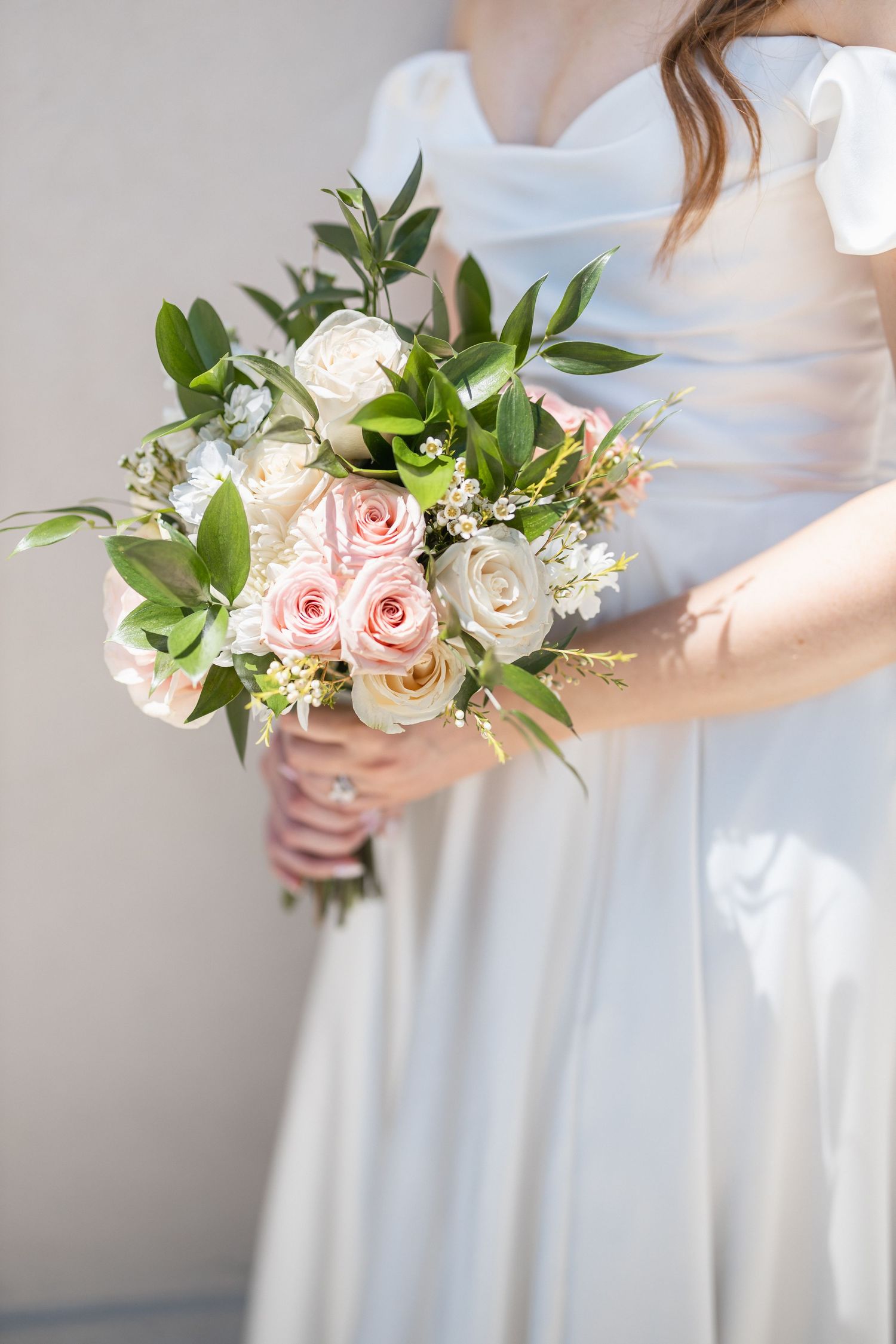Elegant bridal bouquet featuring pink roses and white flowers with fresh green foliage.