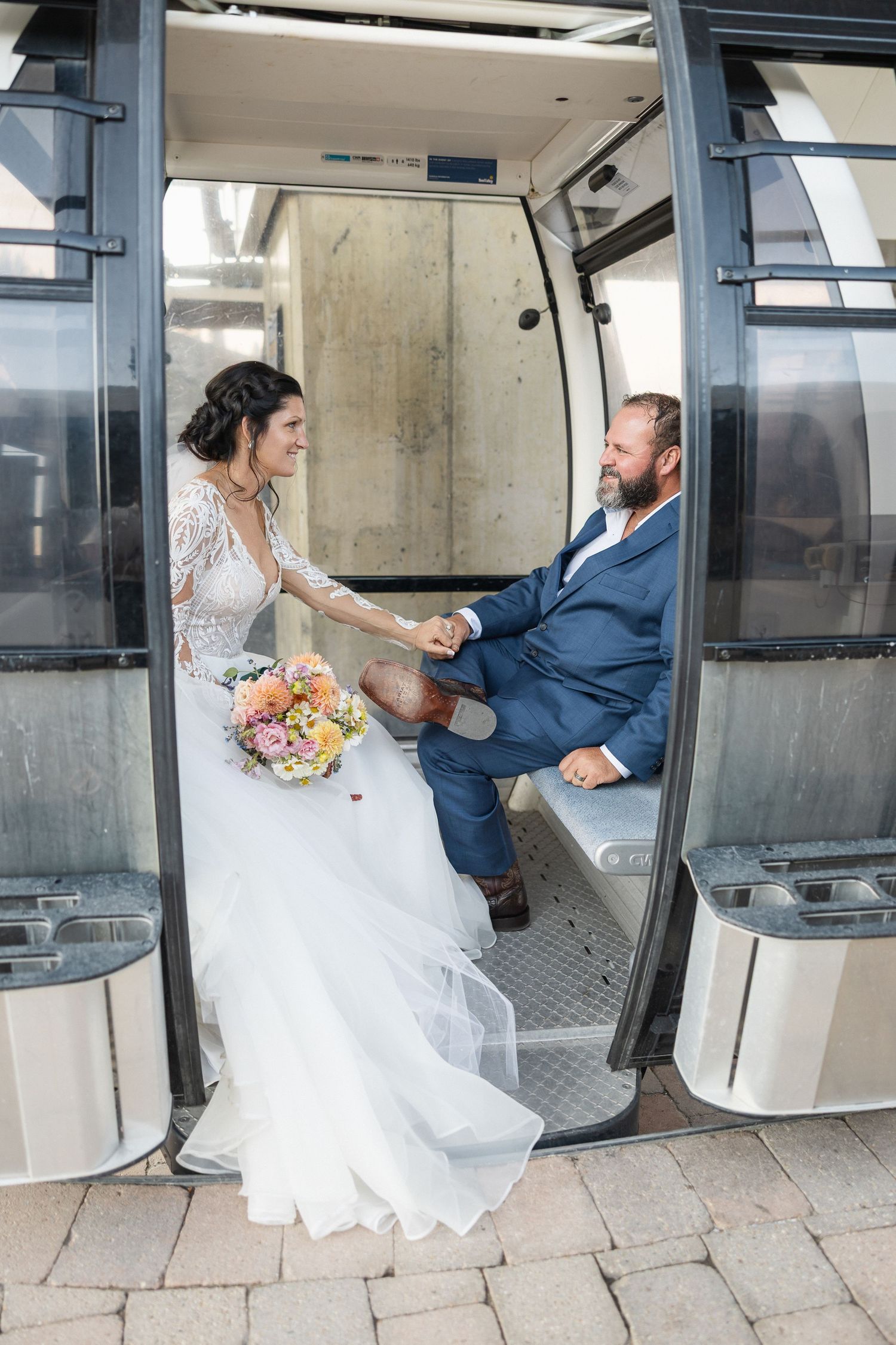 Wedding couple taking photos in modern glass gondola lift station.