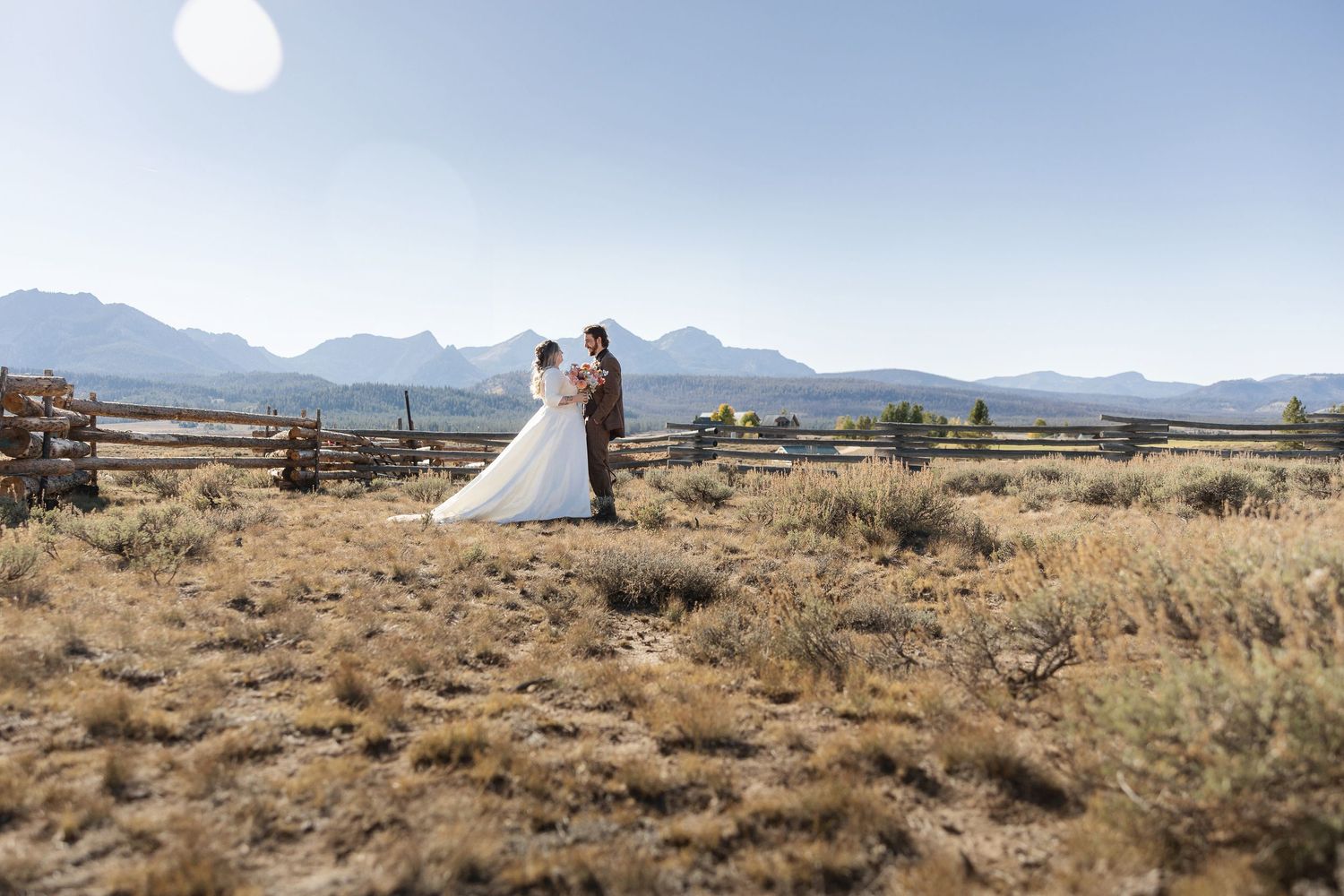 A panoramic view of a desert landscape with mountains and wooden fencing stretching into the distance.