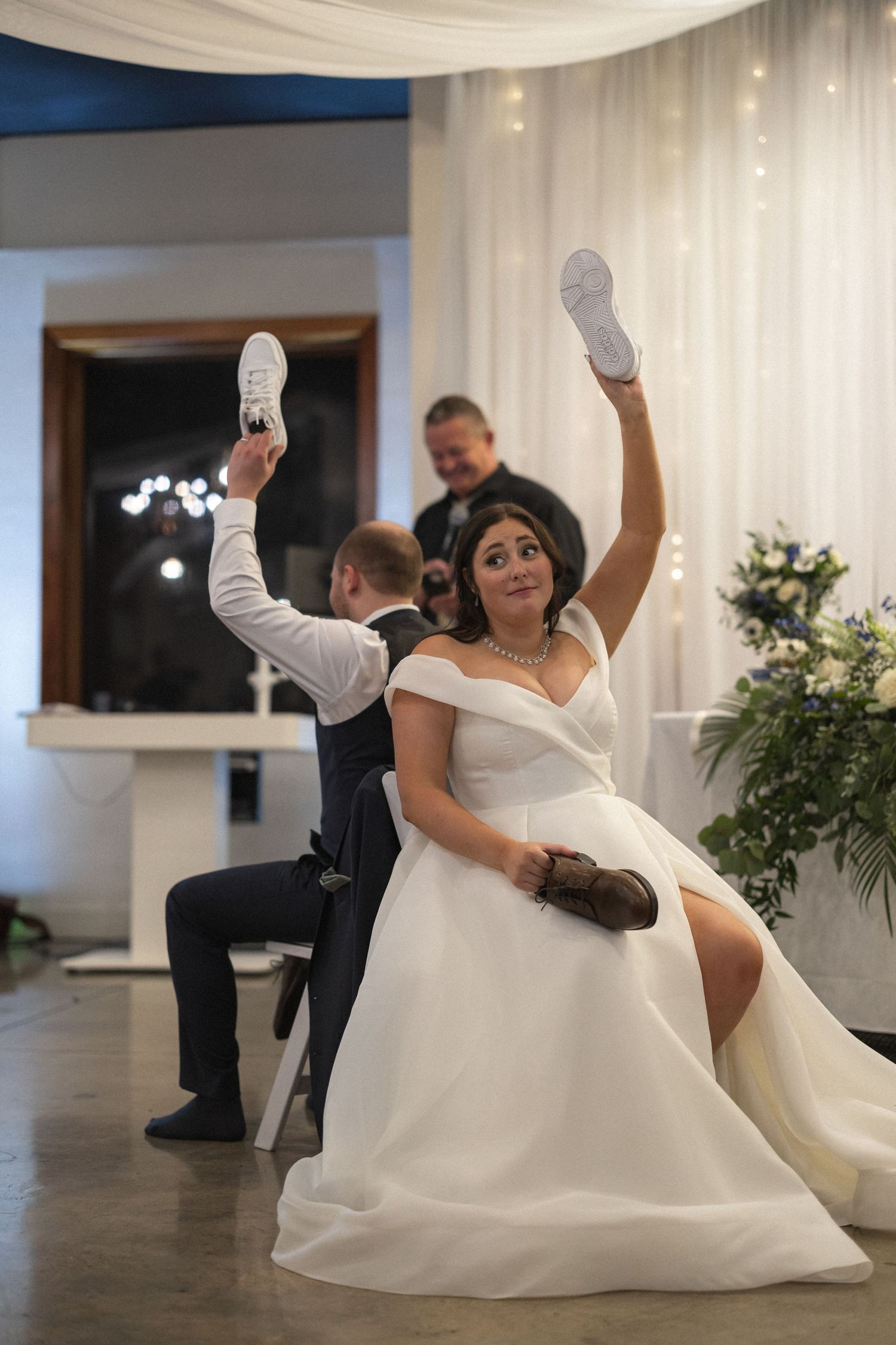 Wedding guests playfully holding up shoes during a reception game or tradition.