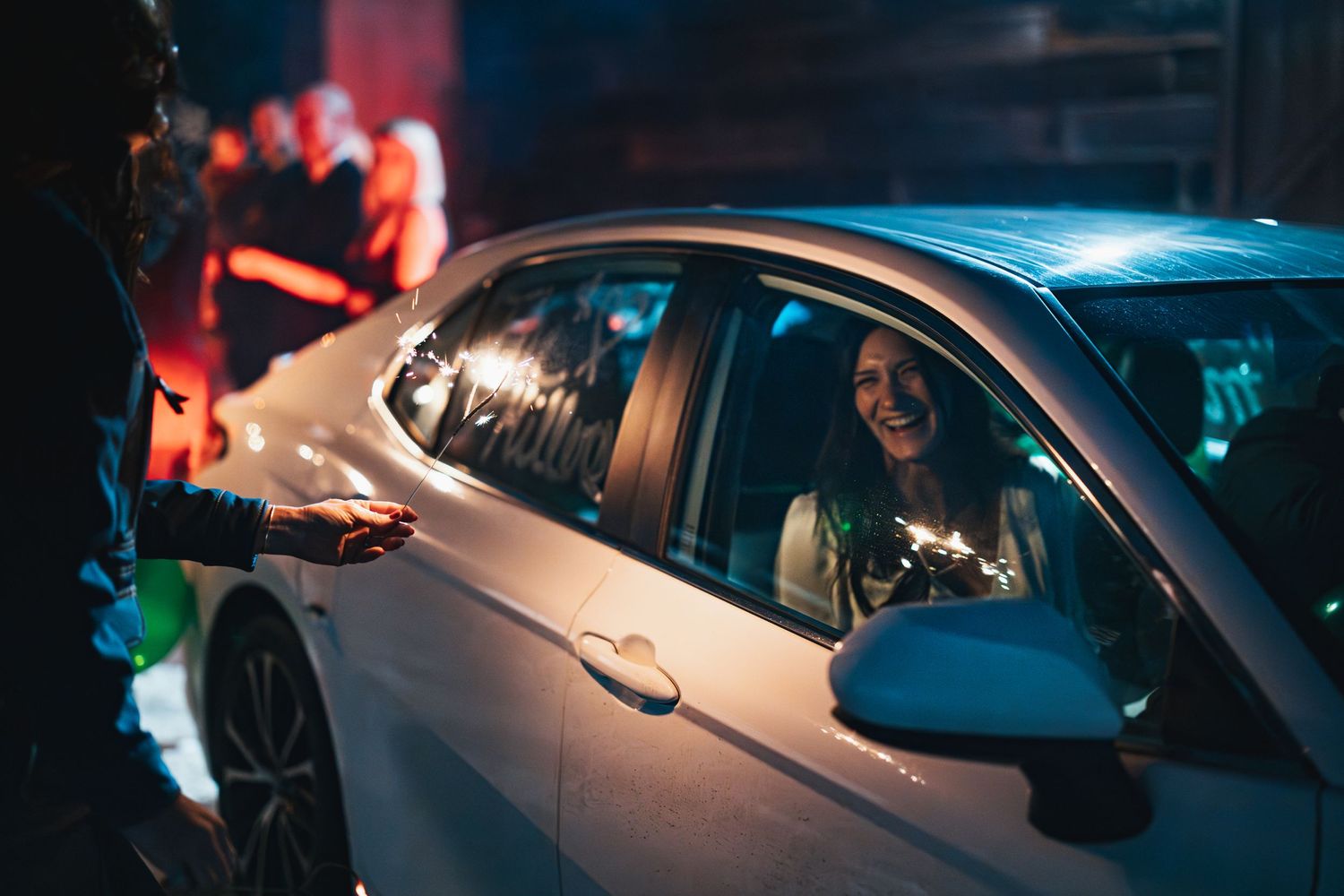 Car decorated with green balloon during nighttime wedding send-off celebration.