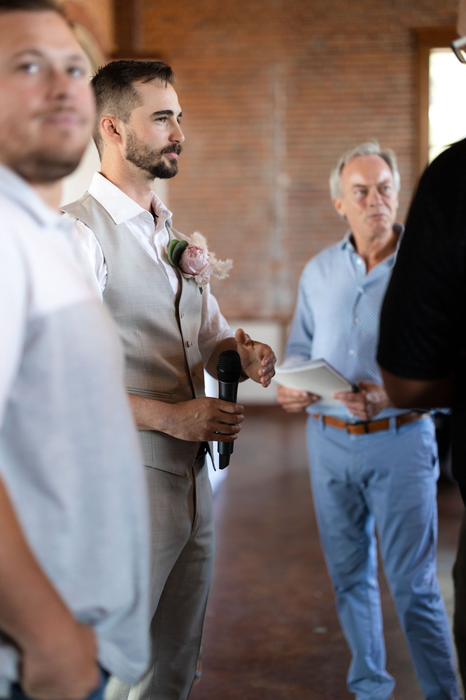 Wedding party members gathered inside brick-walled venue during ceremony preparations.