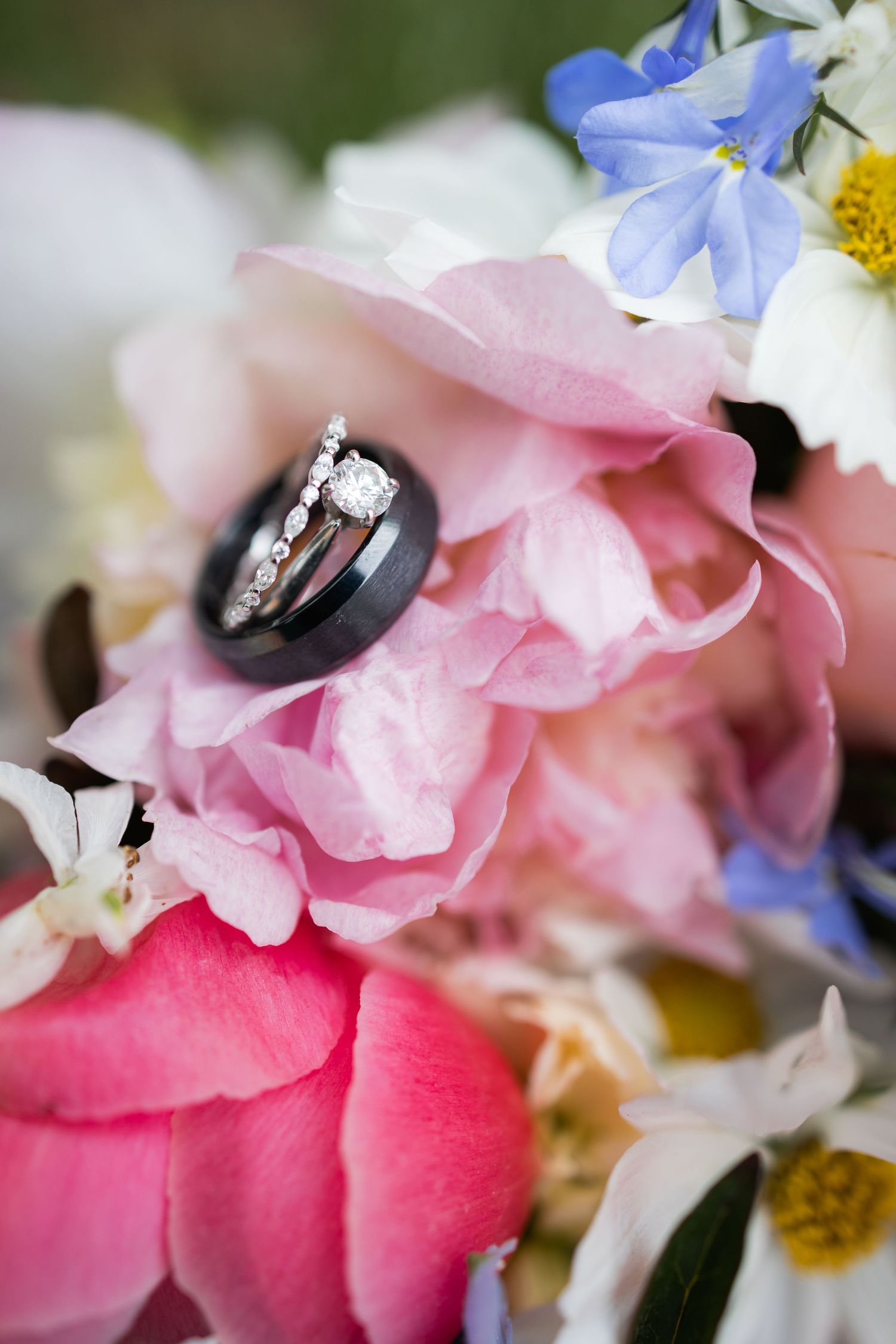 Wedding rings nestled in pink and blue flowers with delicate petals.