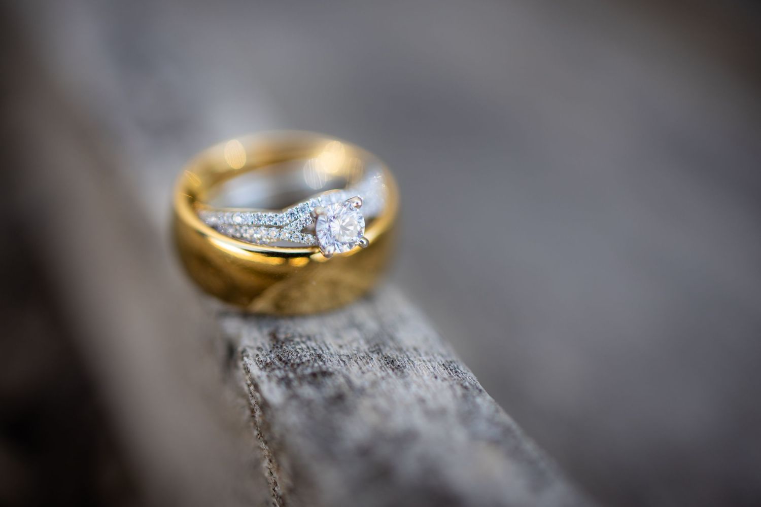 Wedding rings with diamond detail photographed on rustic wood texture.