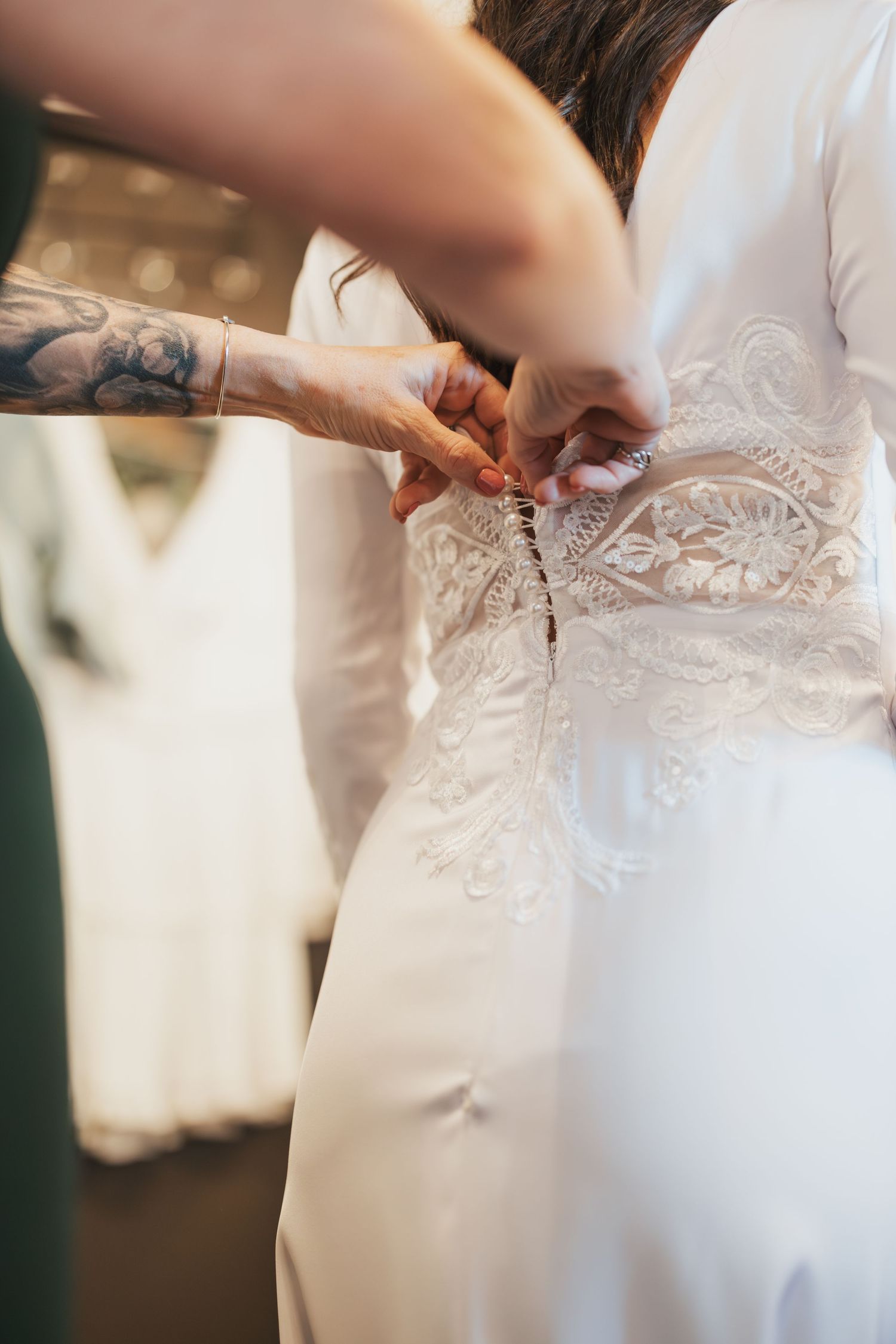 Detail shot of hands lacing up intricate wedding dress.