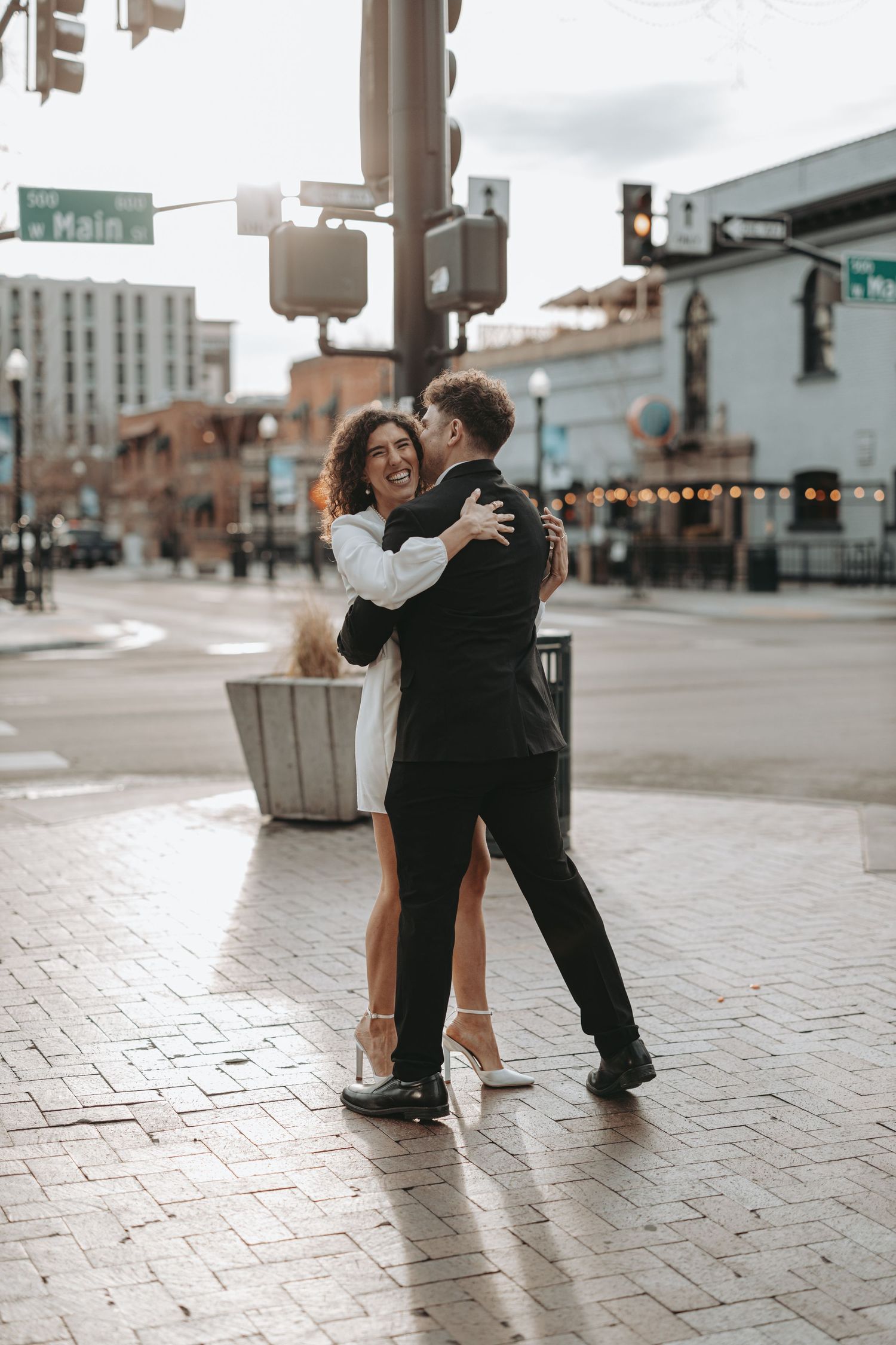 A couple sharing an intimate dance embrace on a city street corner.