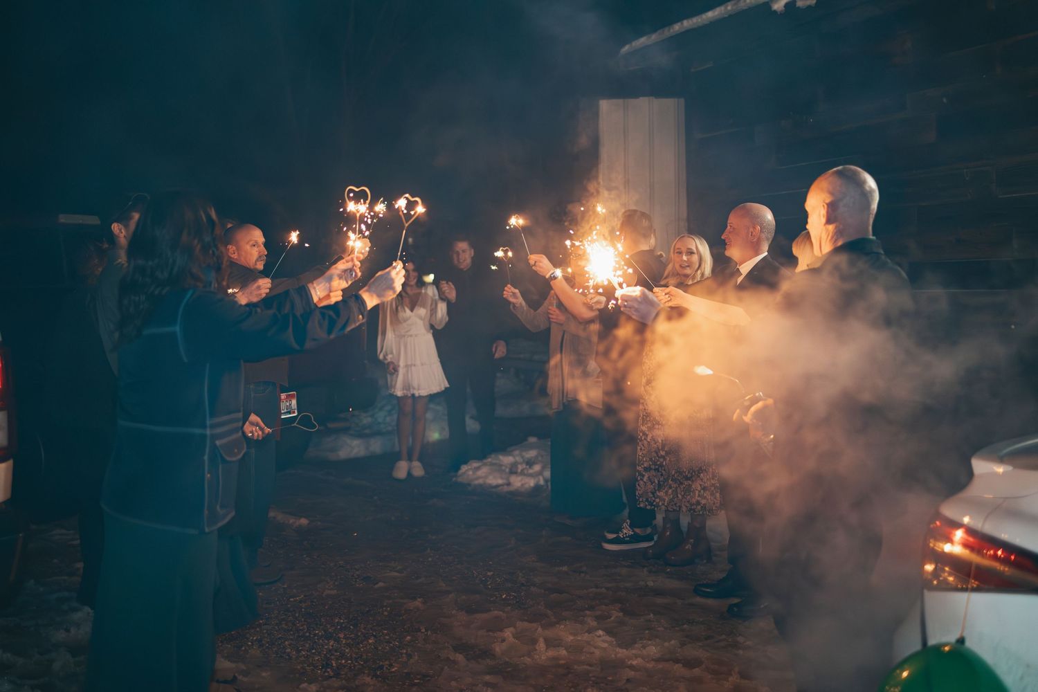 Wedding guests hold sparklers creating a magical nighttime celebration atmosphere.