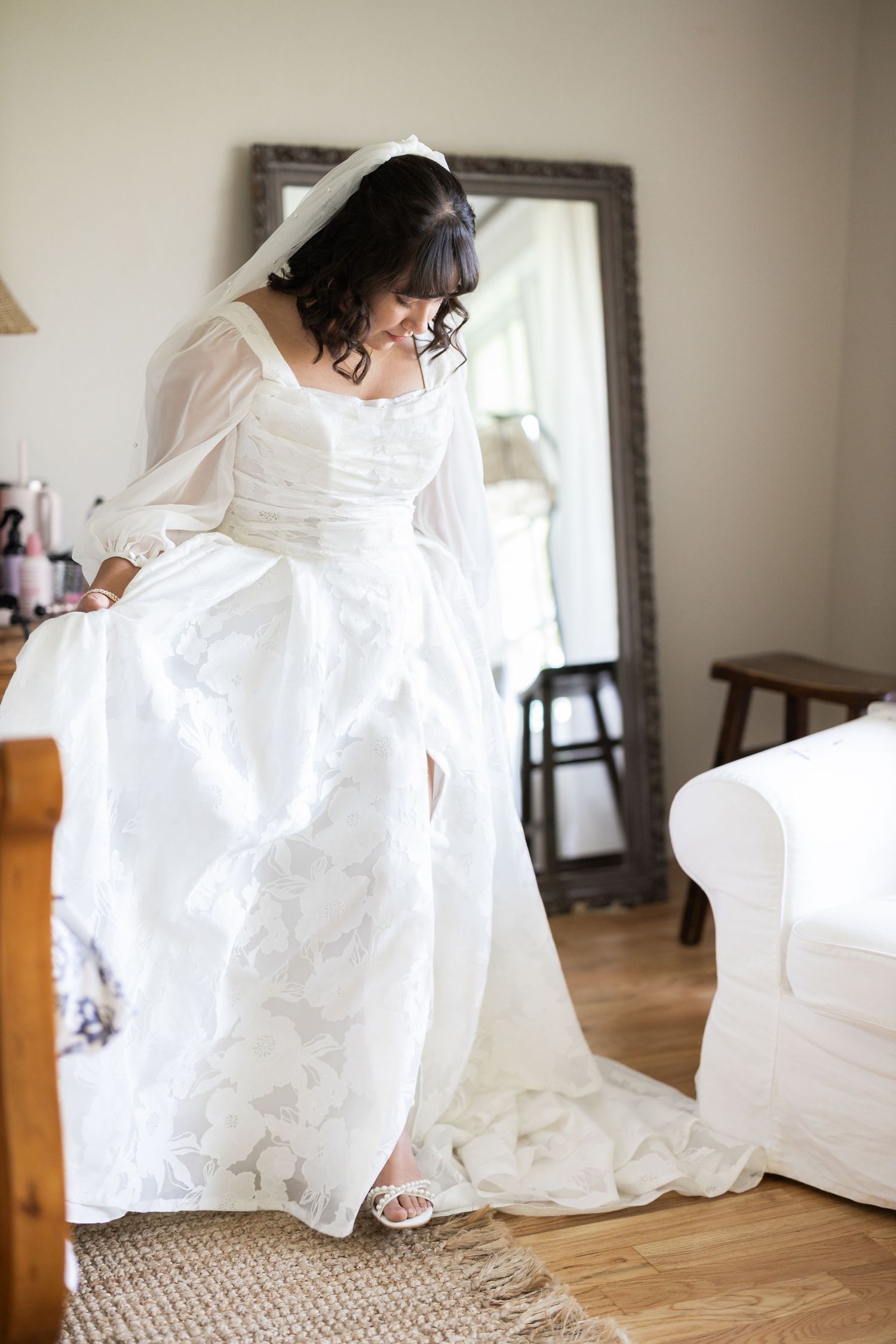 Beautiful wedding dress with intricate details and flowing train on hardwood floor.