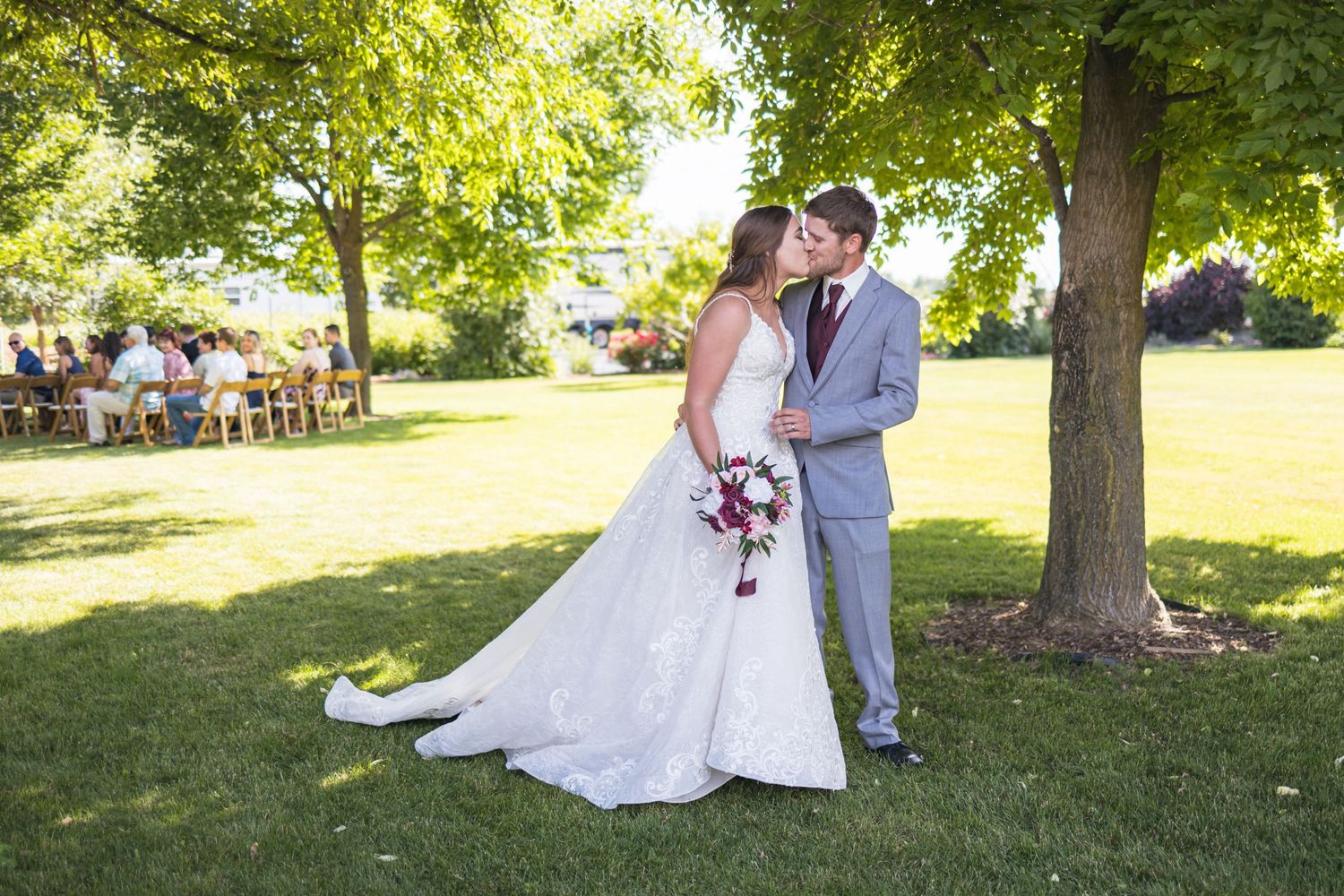 Couple sharing romantic moment on their wedding day in sunny garden setting.