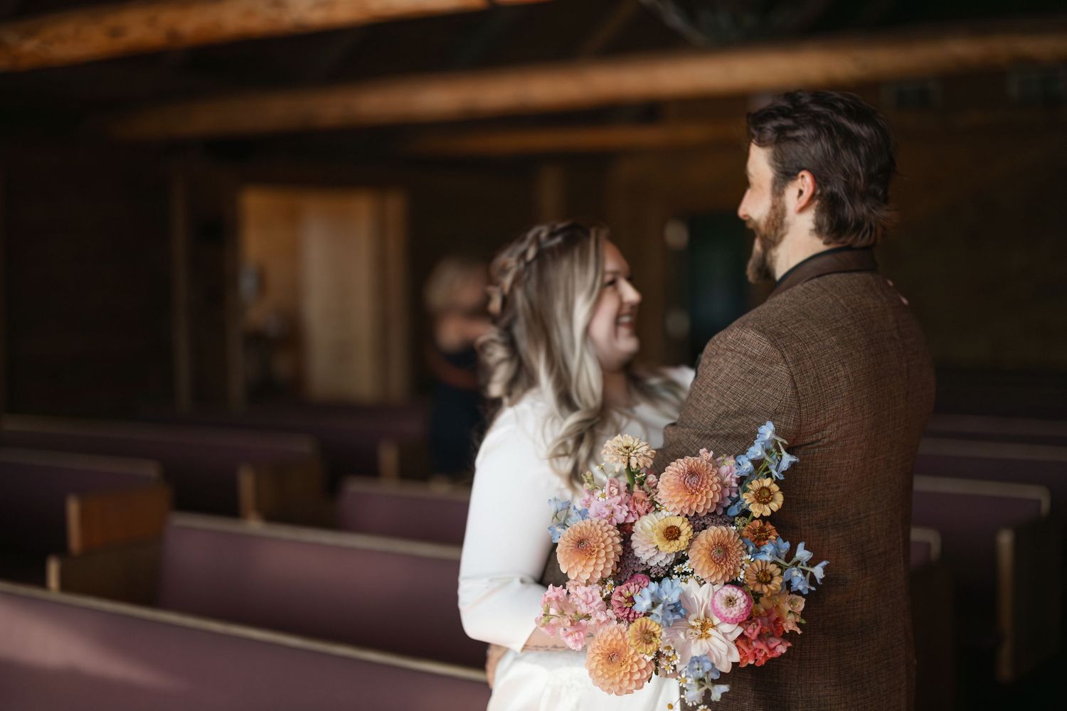 Romantic moment captured in rustic chapel setting with floral details.