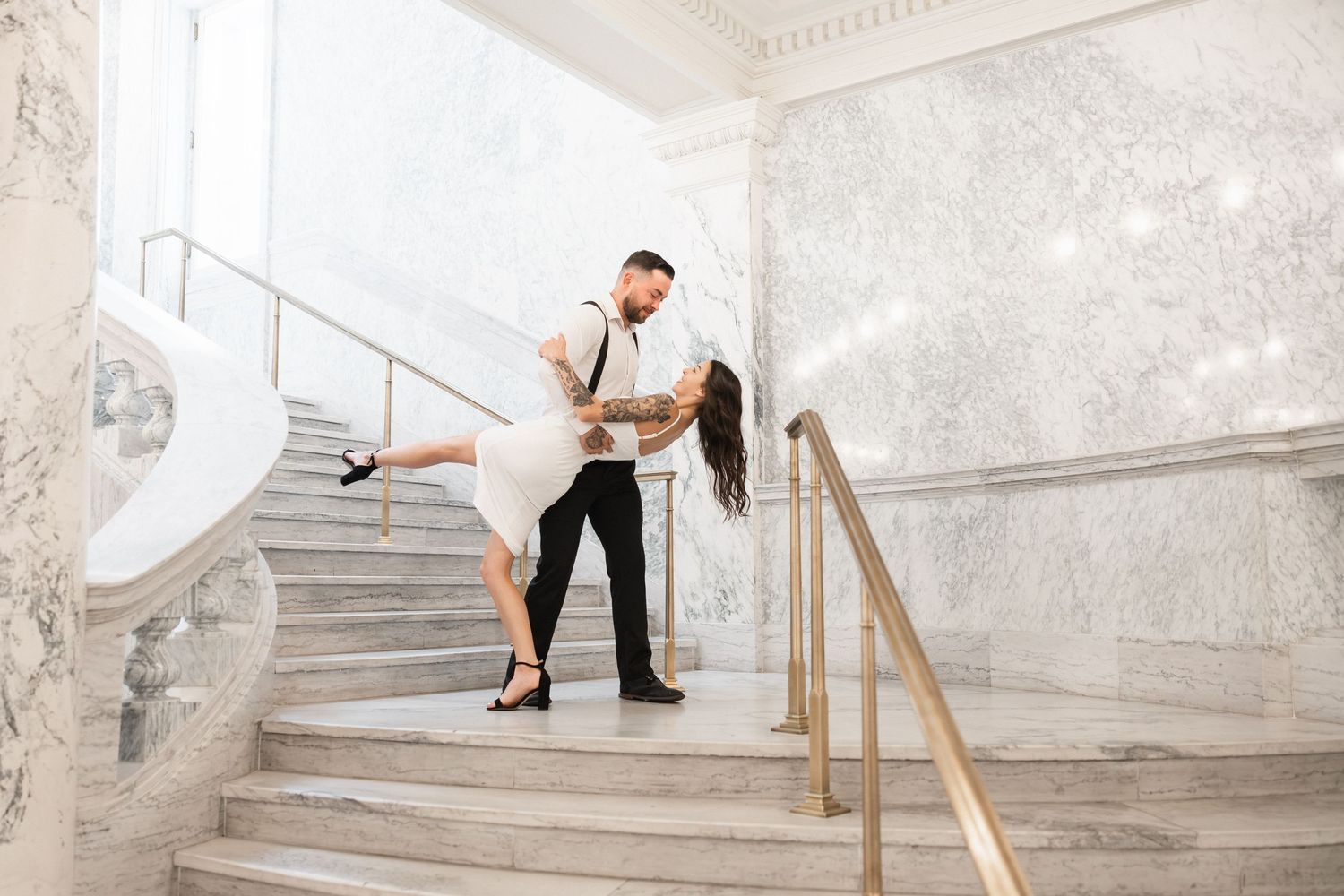 A romantic dance pose on an elegant marble staircase with ornate railings.
