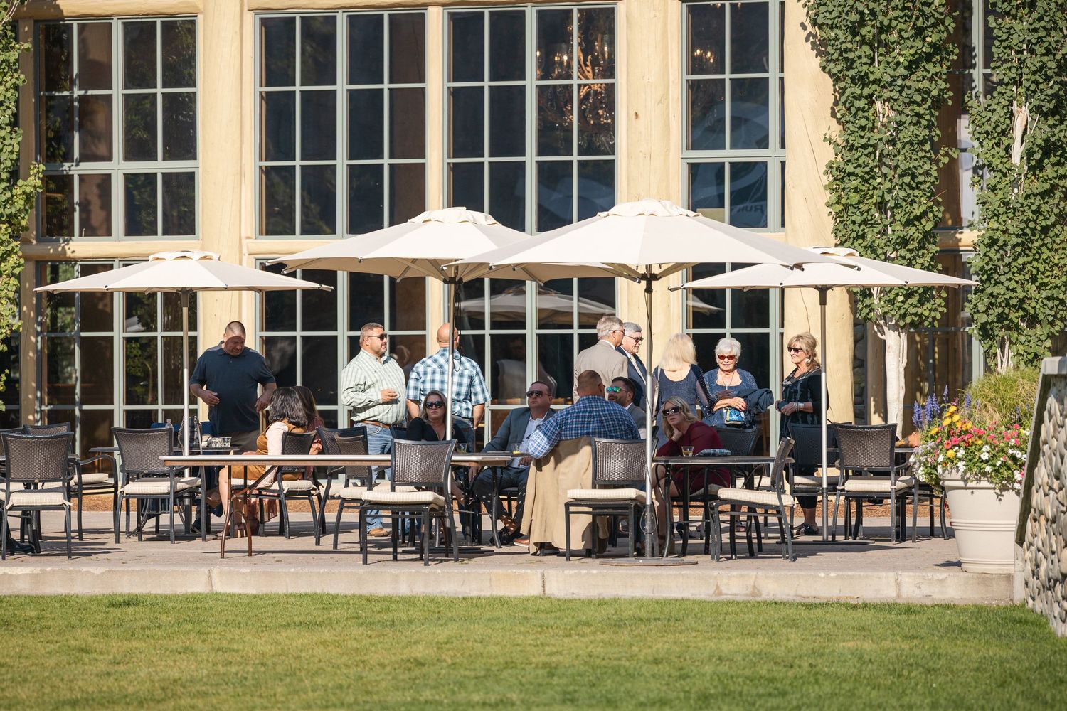 Exterior view of a modern lodge building with outdoor dining area and umbrellas.
