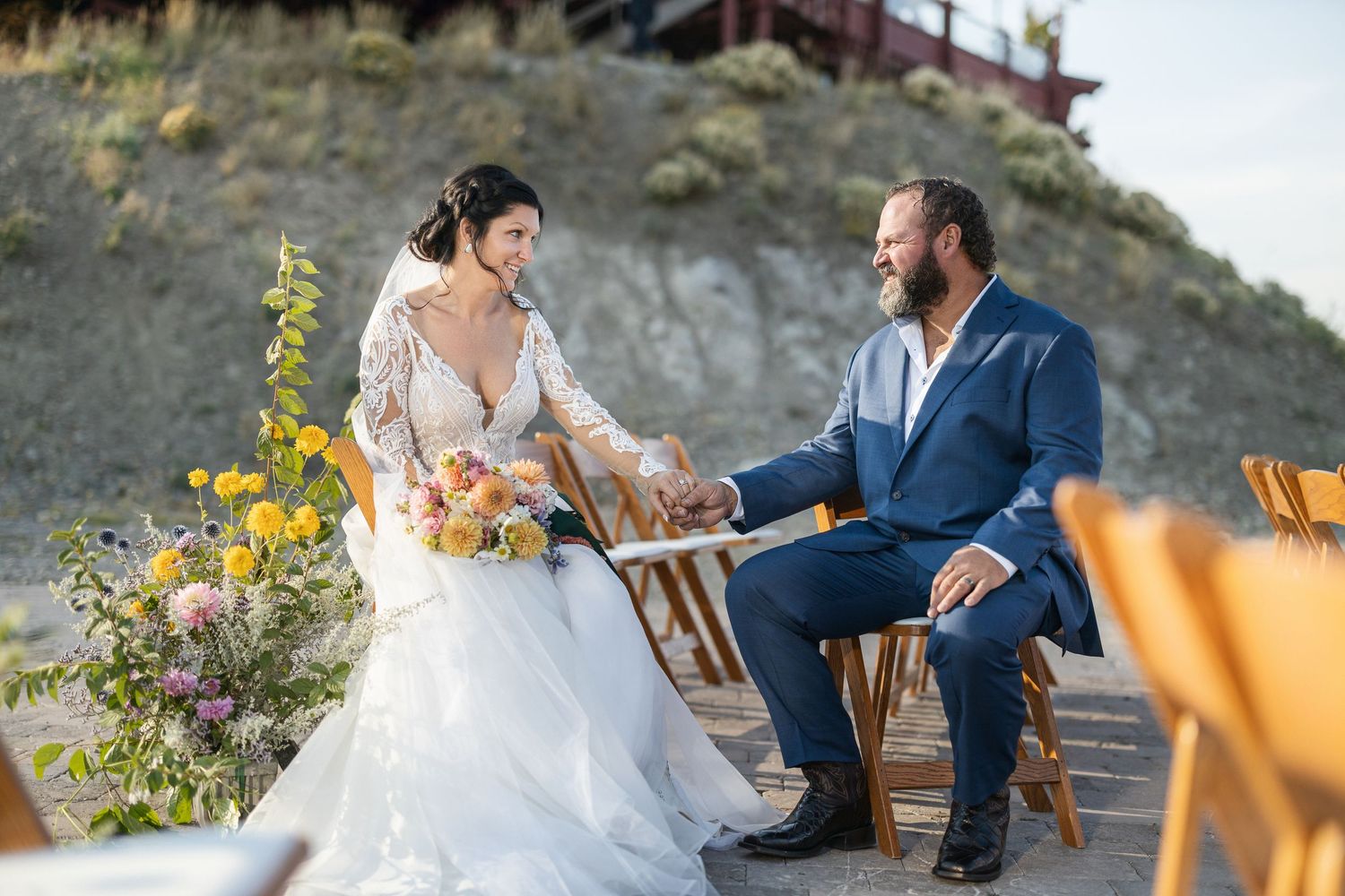 Outdoor mountain wedding ceremony with rustic wooden chairs and natural decor.