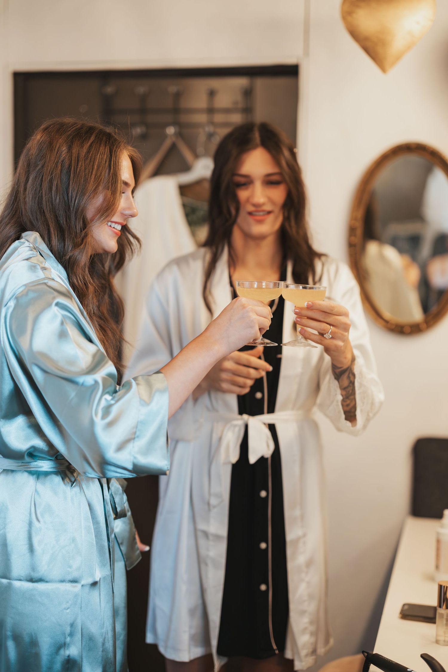 Wedding preparation scene with two people in robes toasting with champagne glasses.