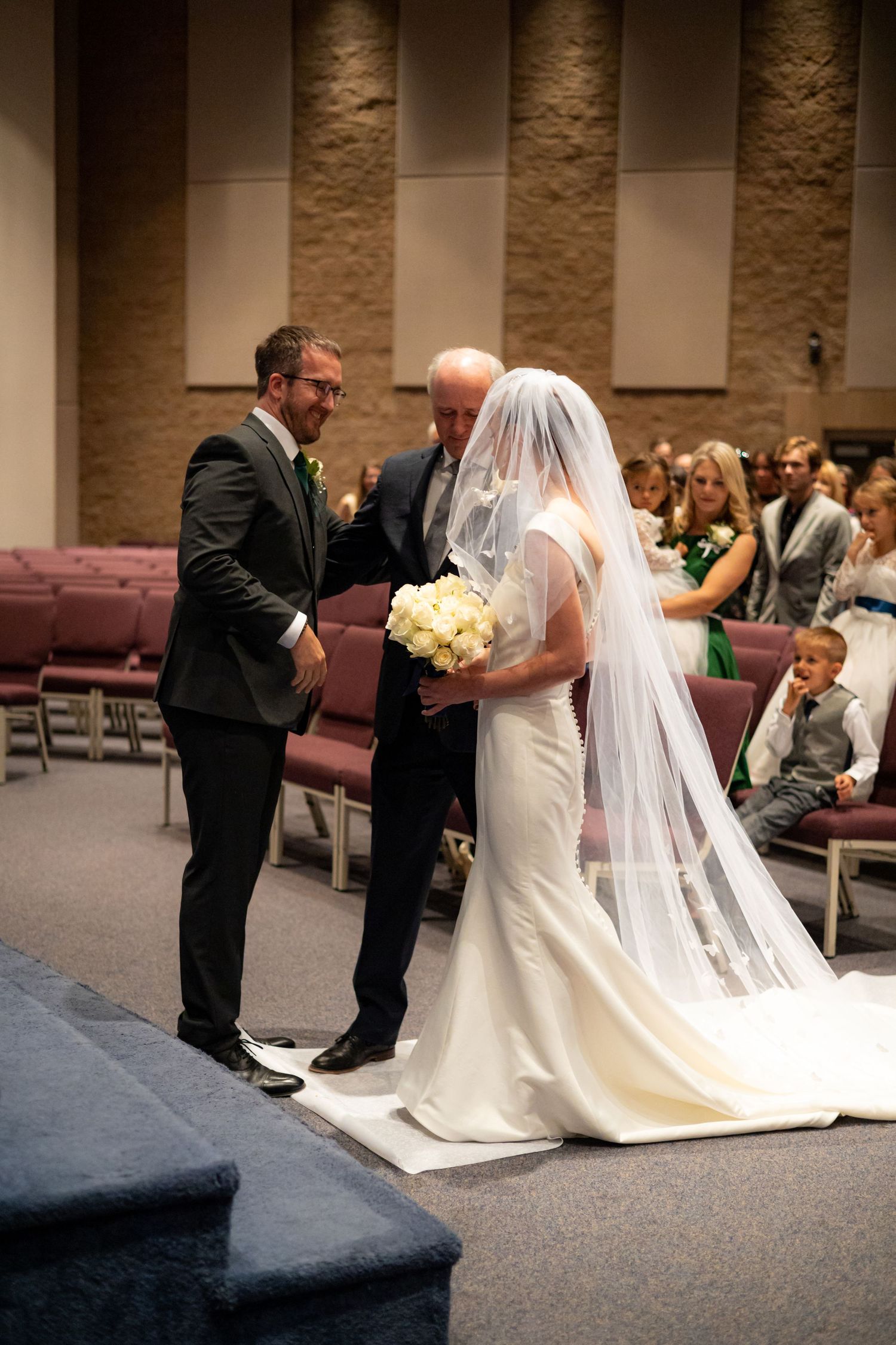 Special prayer moment during wedding ceremony with participants kneeling at church altar.