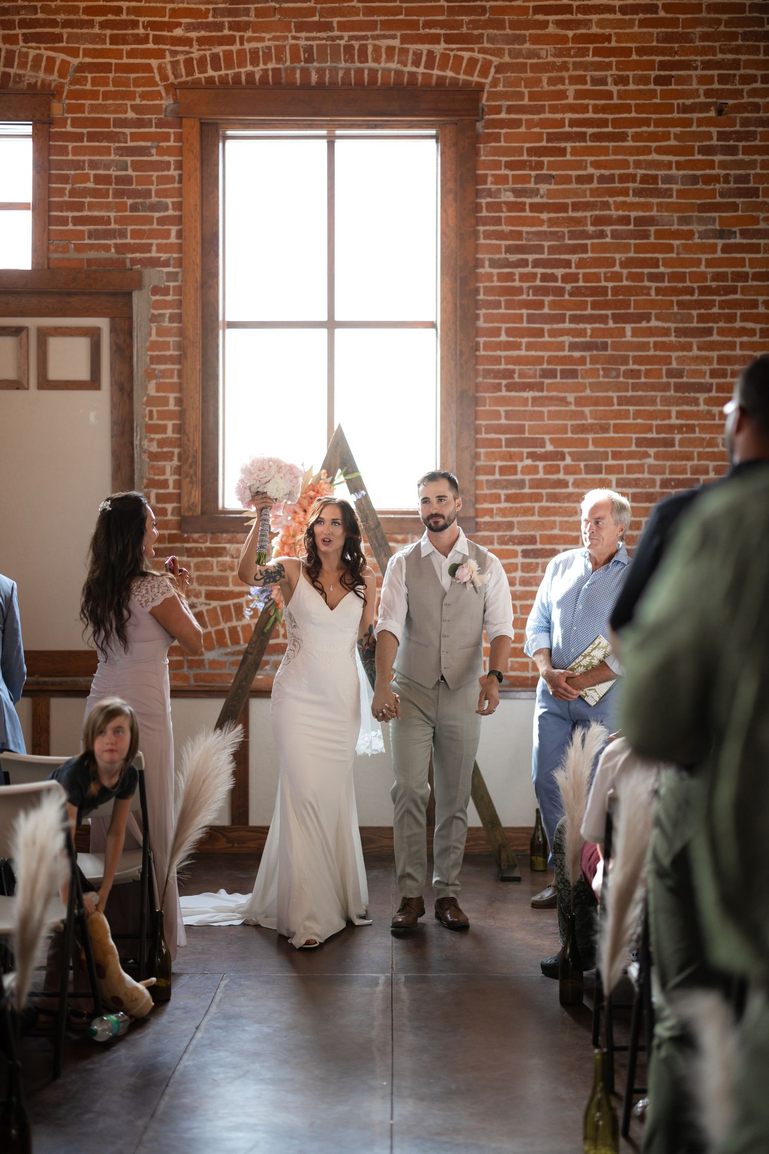 Wedding ceremony in progress inside an industrial-style venue with exposed brick walls.