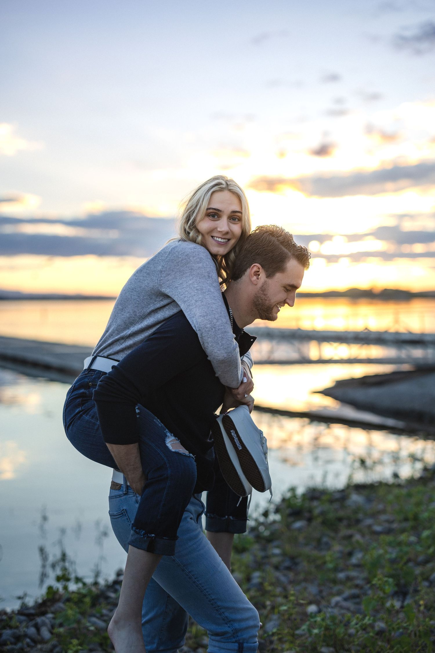 Playful piggyback ride against a waterfront sunset backdrop.