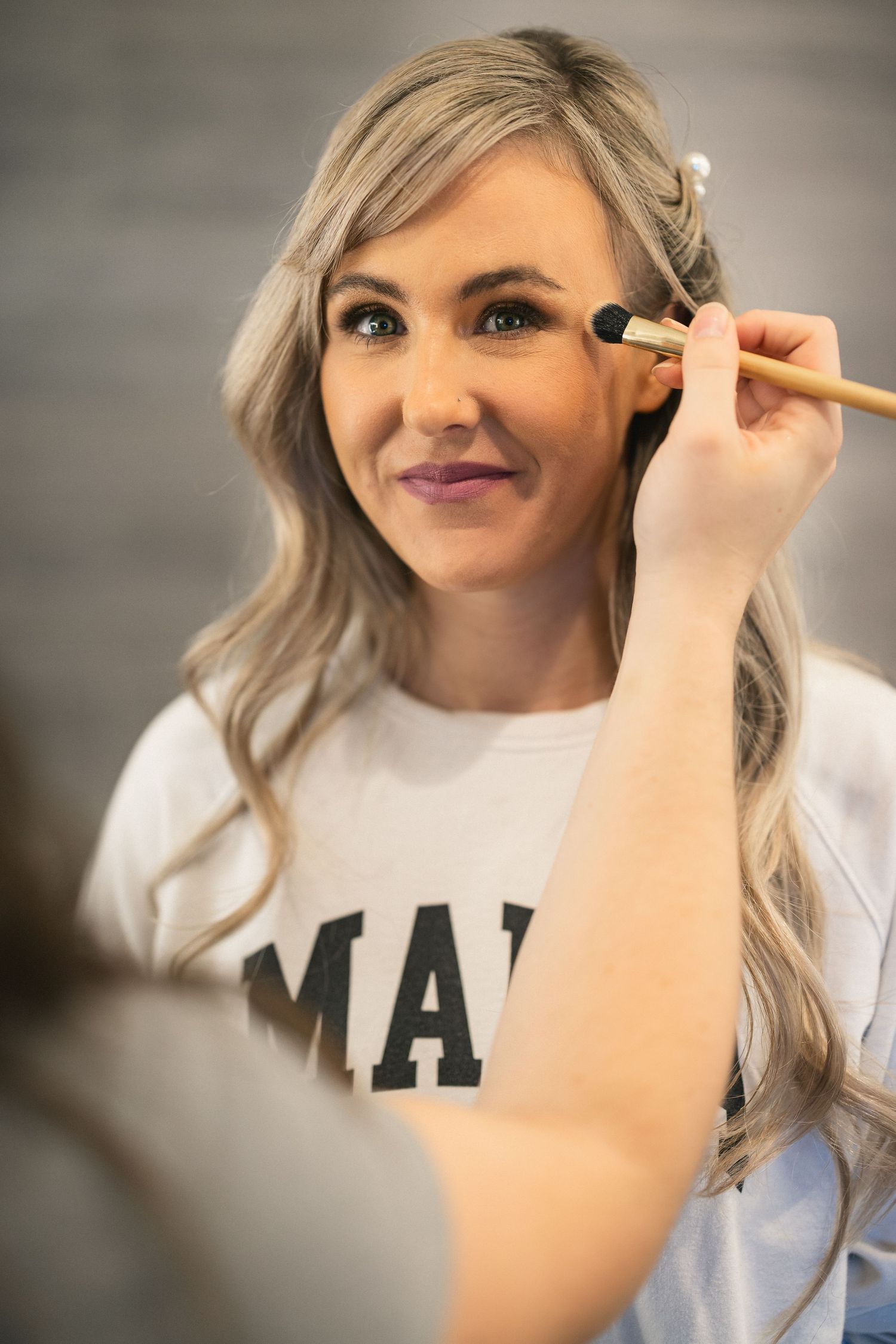 Wedding day makeup preparation in progress with brush application.