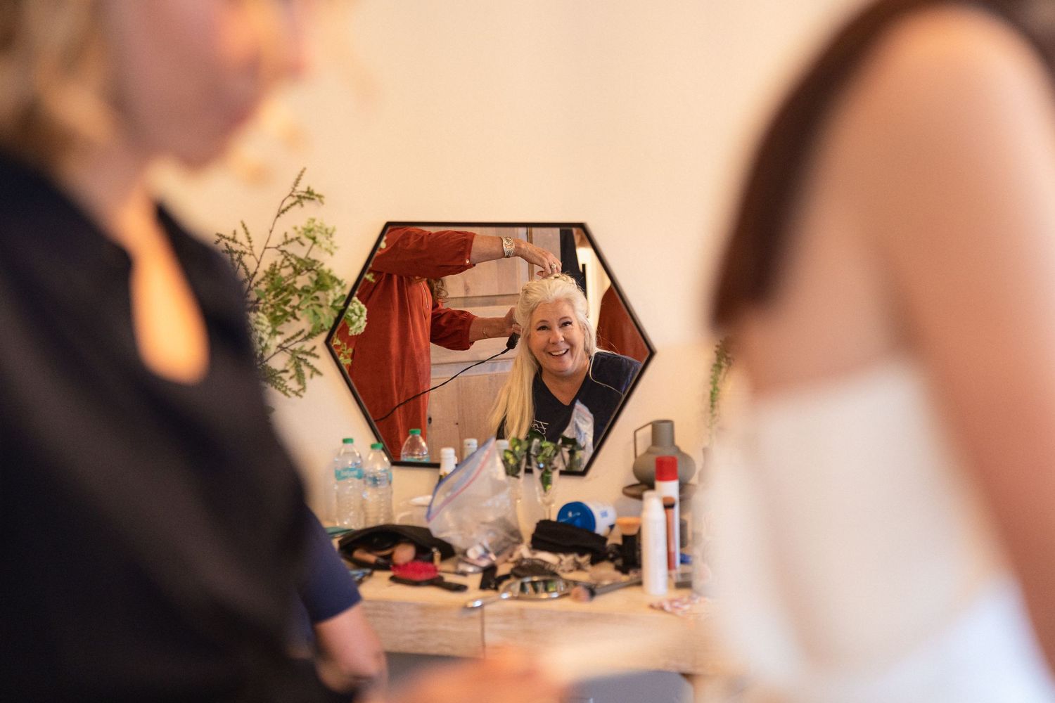 Wedding preparations reflected in a decorative mirror with flowers and decor visible.