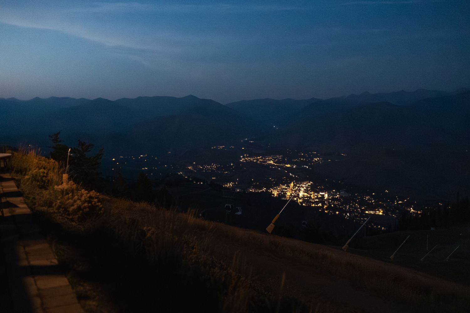 Nighttime cityscape view of mountain valley with twinkling lights below.