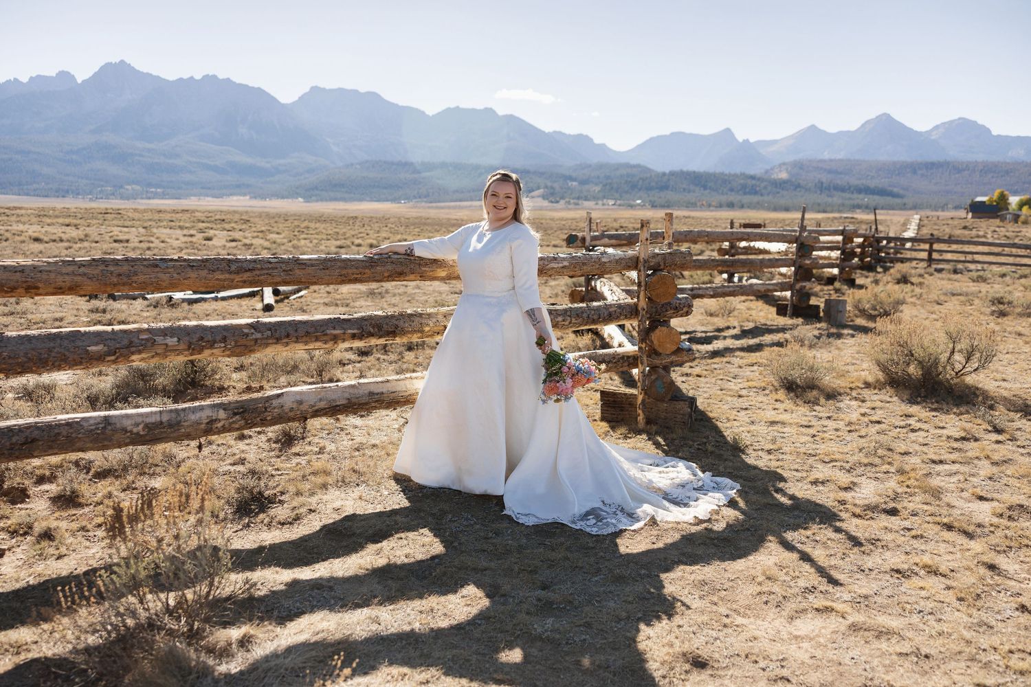 A scenic desert landscape with mountains in the background and a rustic wooden fence in the foreground.