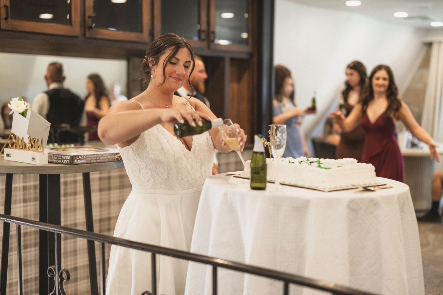 A bride in a white dress pours champagne at an elegant wedding reception.