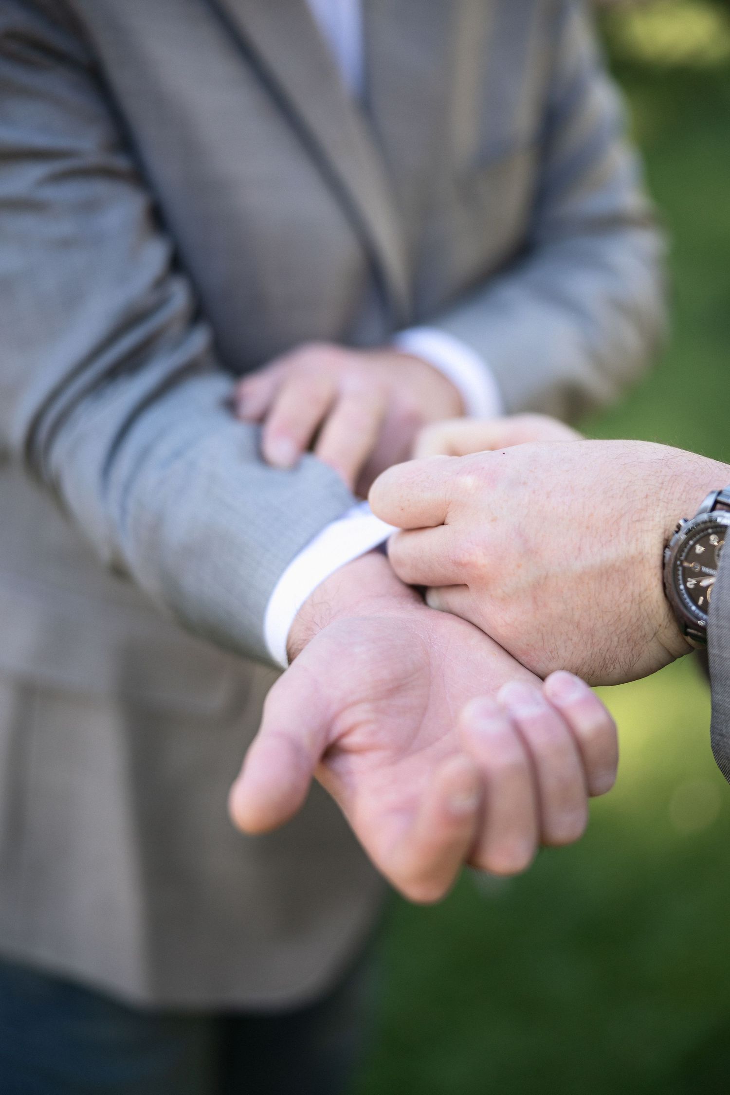 Close-up of hands adjusting formal suit cuff and watch.
