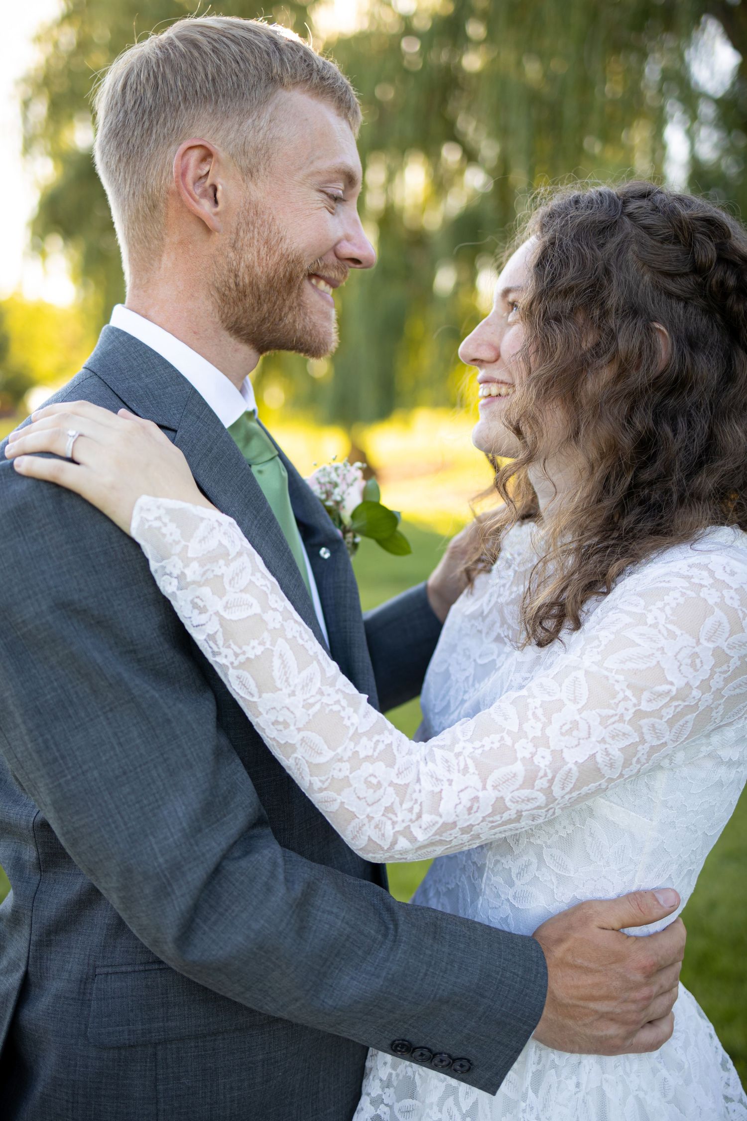 Joyful wedding moment captured between couple in elegant attire against natural backdrop.