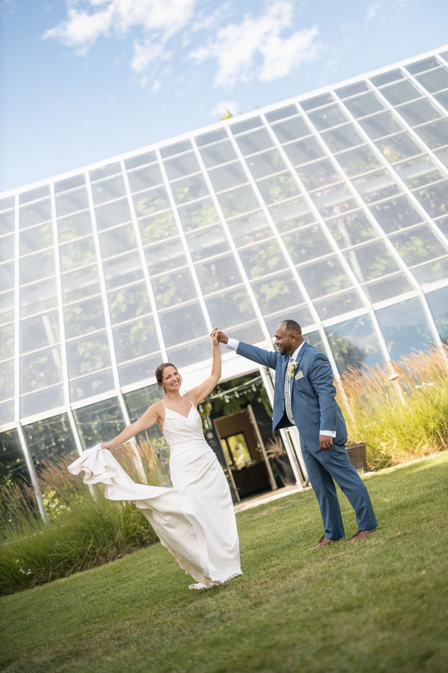 Dancing sequence of wedding couple with flowing dress against glass greenhouse structure.
