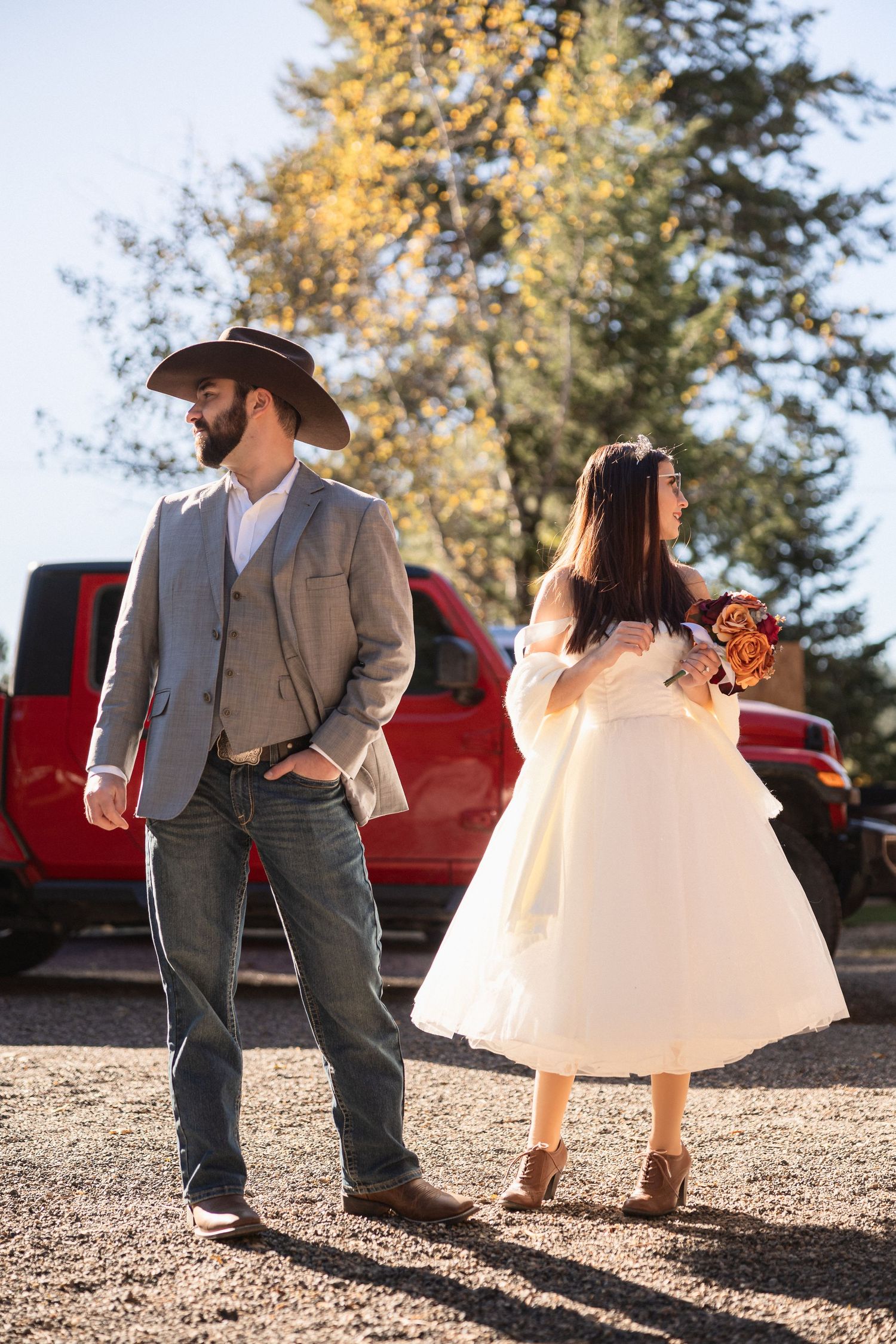 A couple dances in a rustic outdoor setting with a red truck visible in the background.