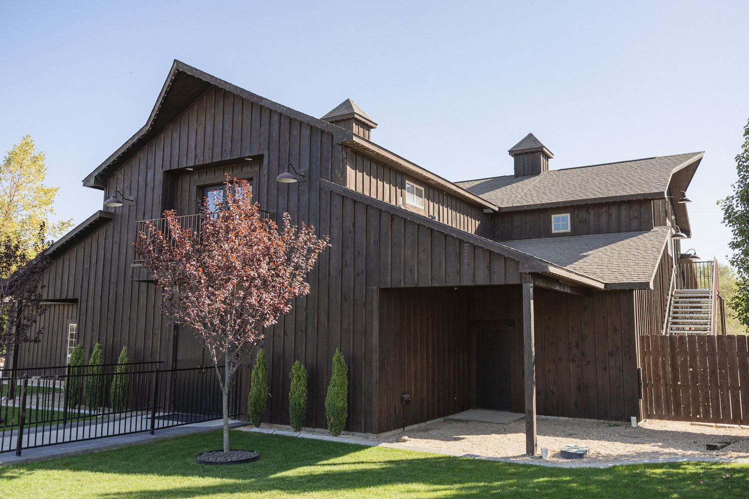 A modern rustic barn venue with dark wood siding and architectural details.