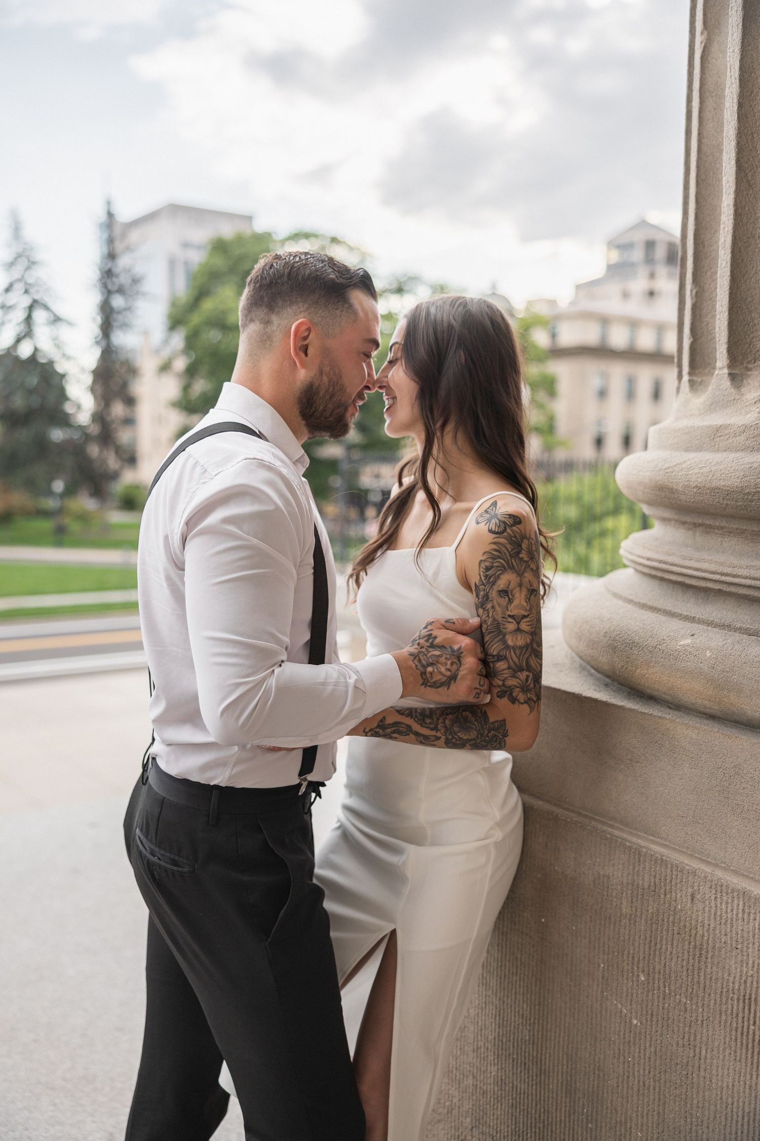 Romantic couple sharing intimate moments against classic stone columns at a grand building entrance.