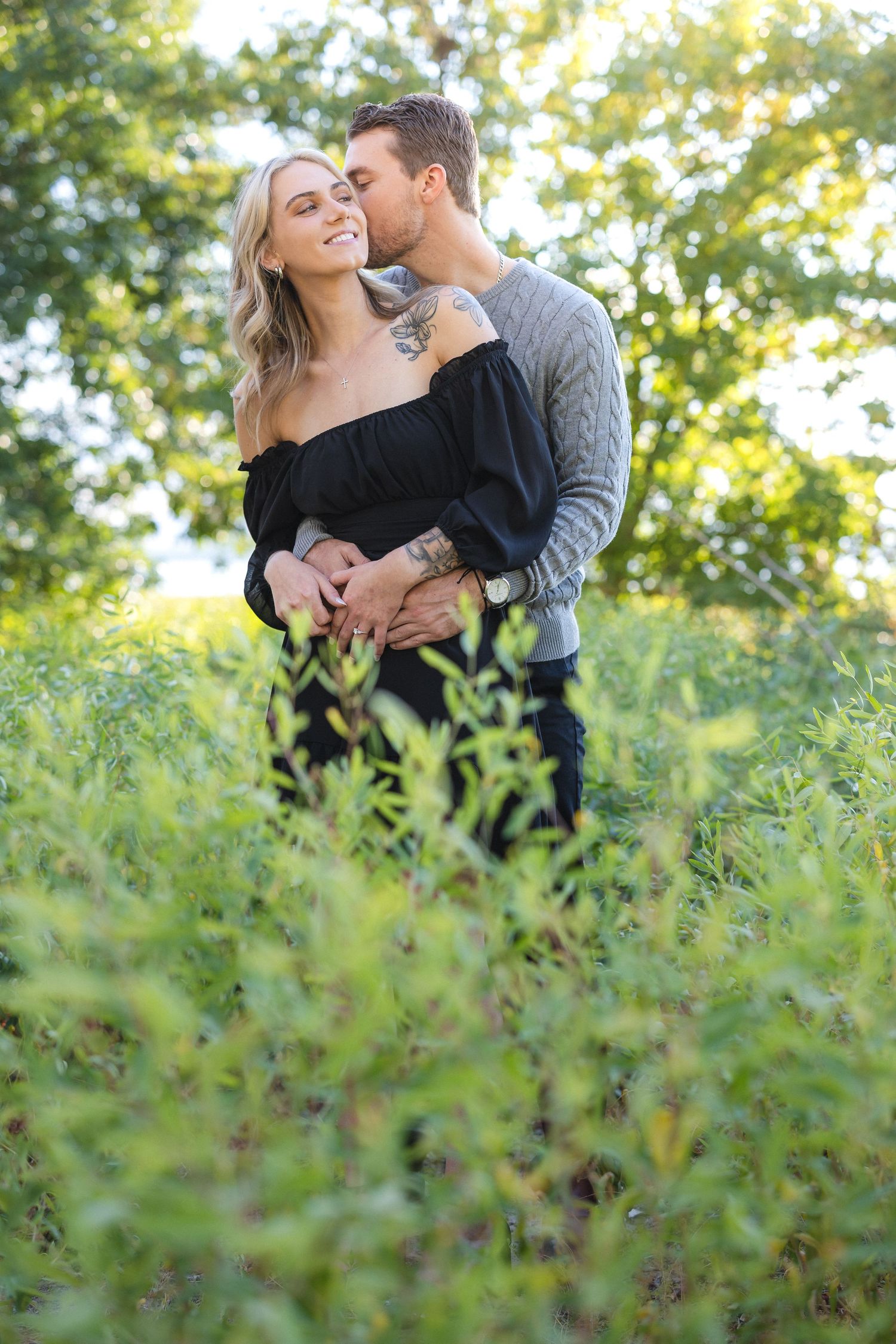 Intimate portrait of couple among green foliage with natural sunlight.