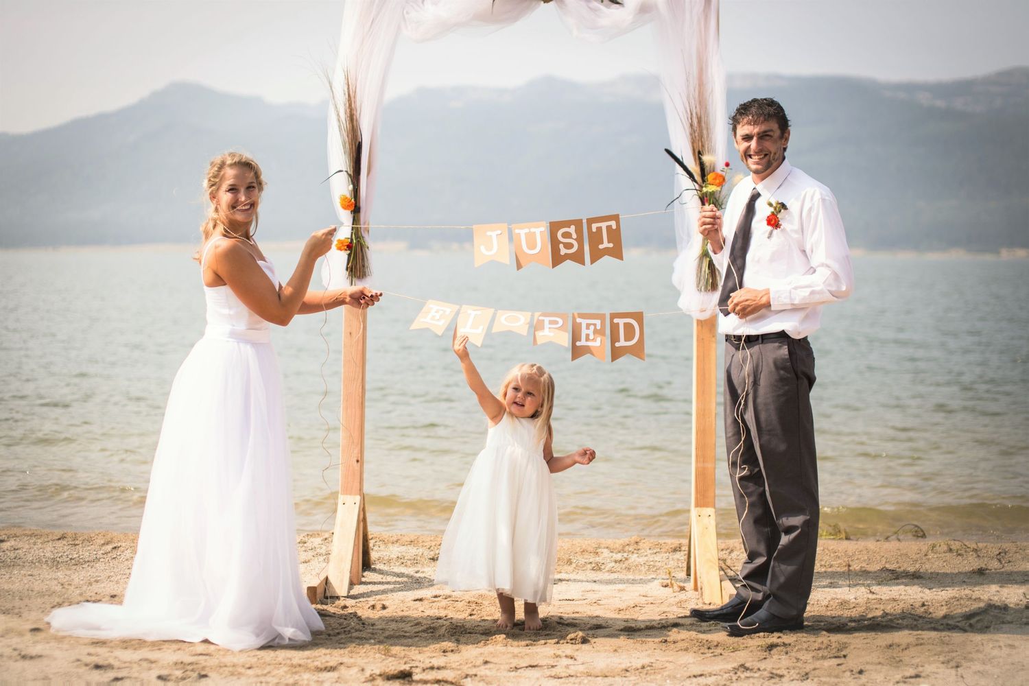 Family stands by beach wedding arch with 