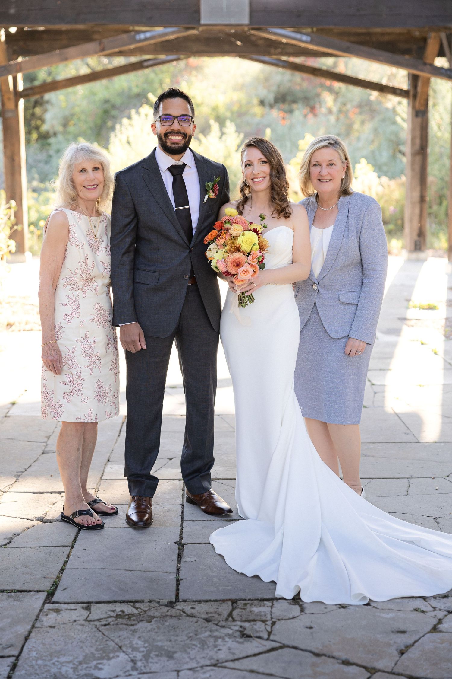 Formal family wedding portrait under wooden pavilion with stone floor.