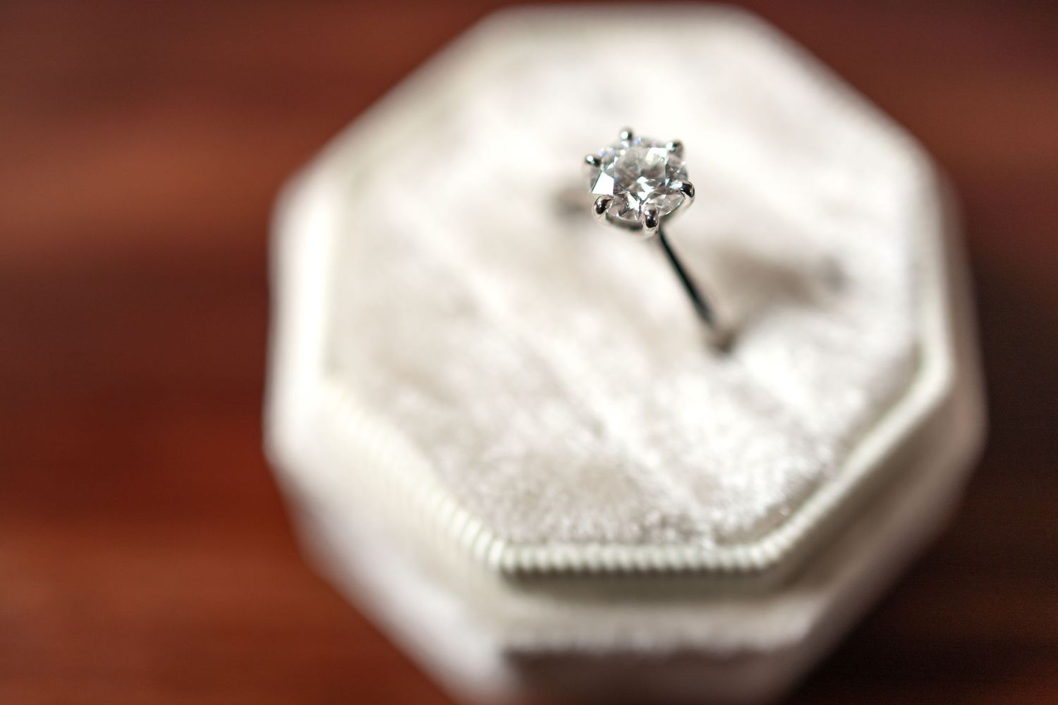 Diamond solitaire engagement ring in white hexagonal box with soft focus effect.