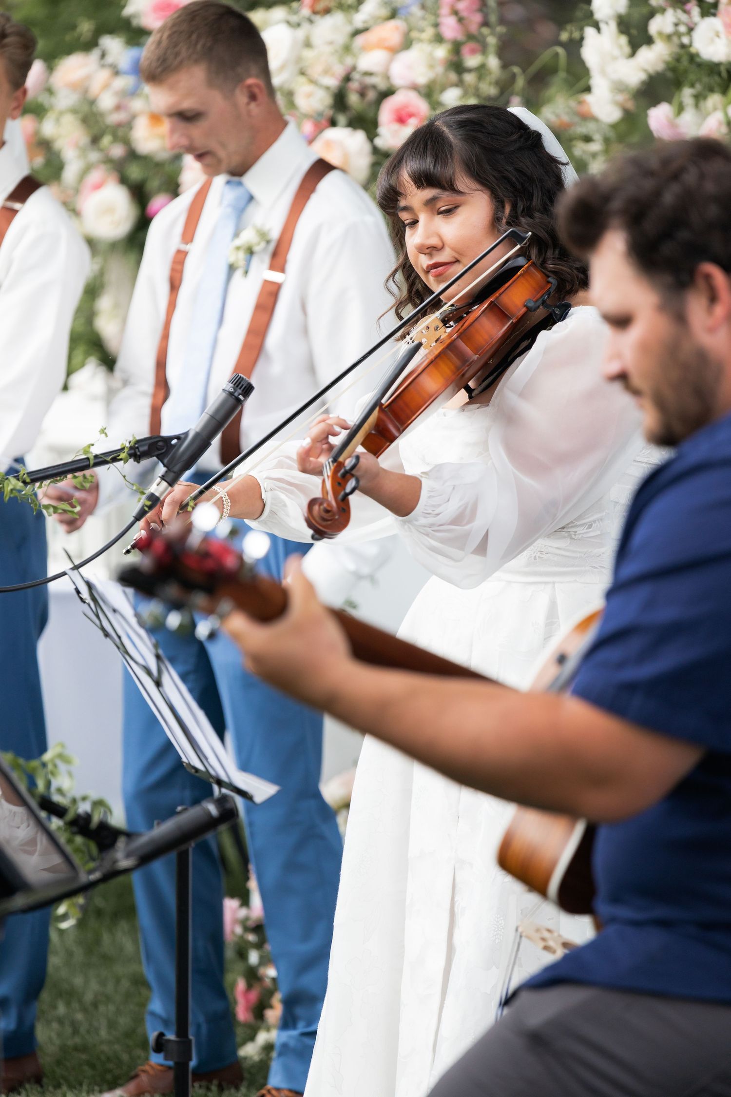 Musicians perform with violin and guitar during outdoor wedding ceremony.