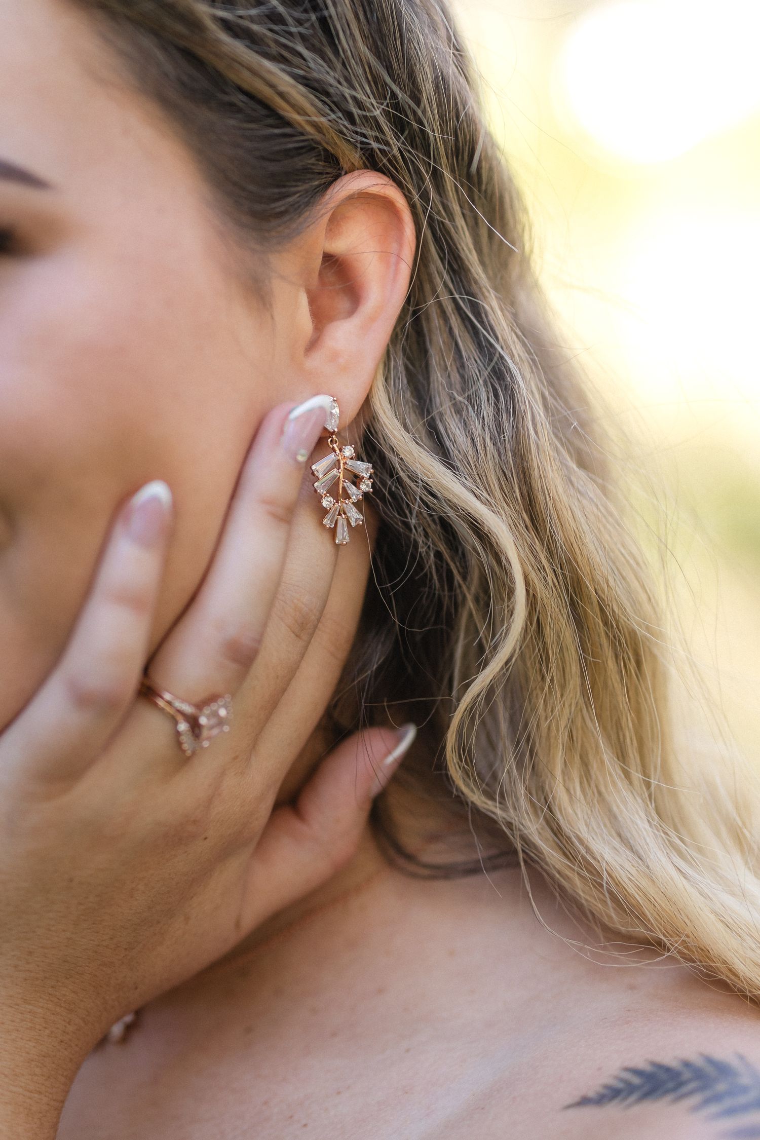 Close-up of elegant crystal earring and wavy blonde hair.