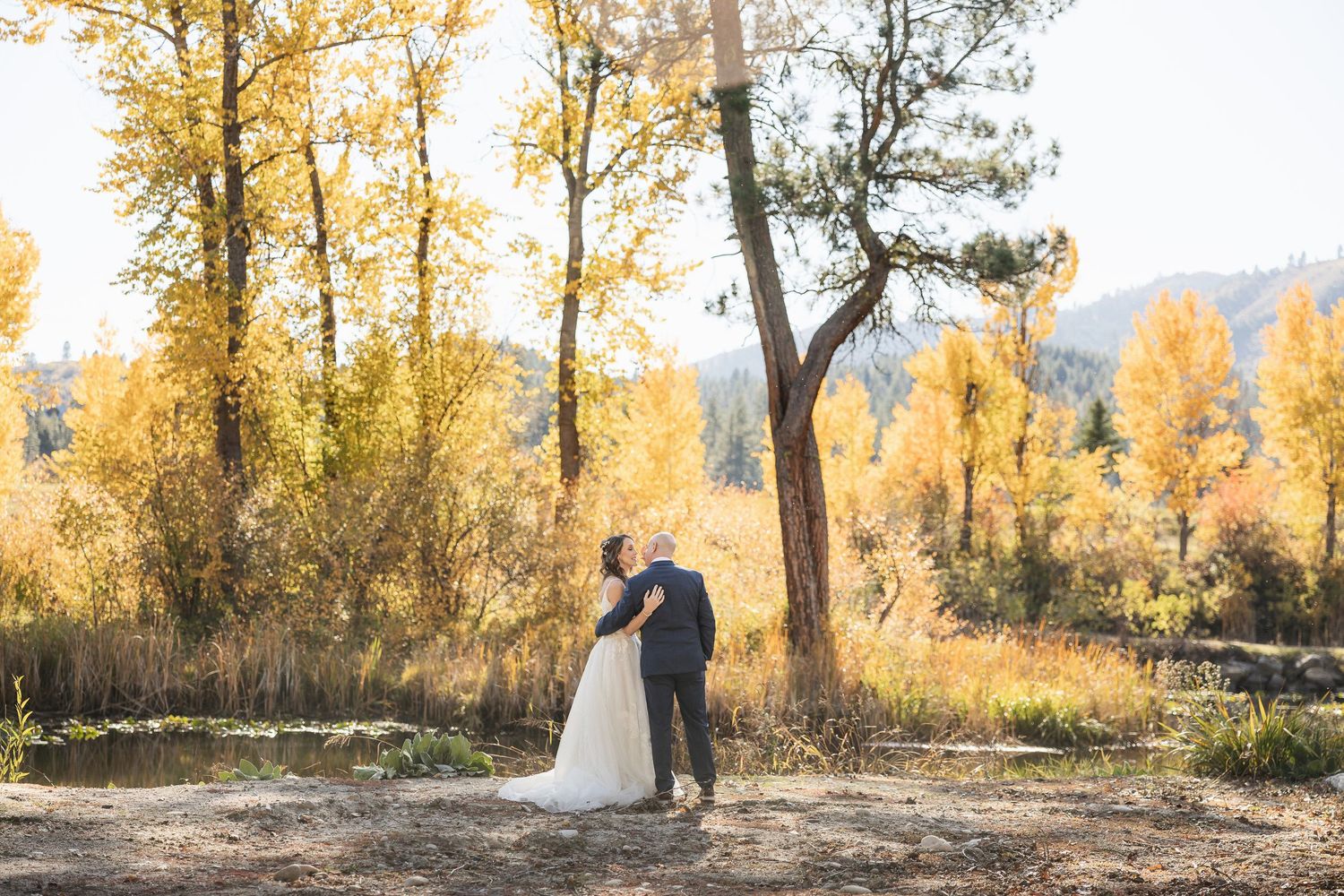 Fall wedding scene with golden trees and mountain landscape in background.