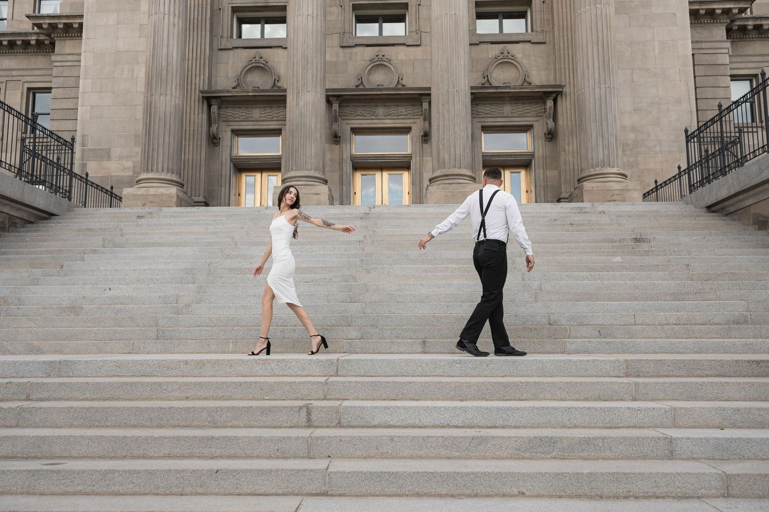 Couple walking down wide stone steps of historic building.