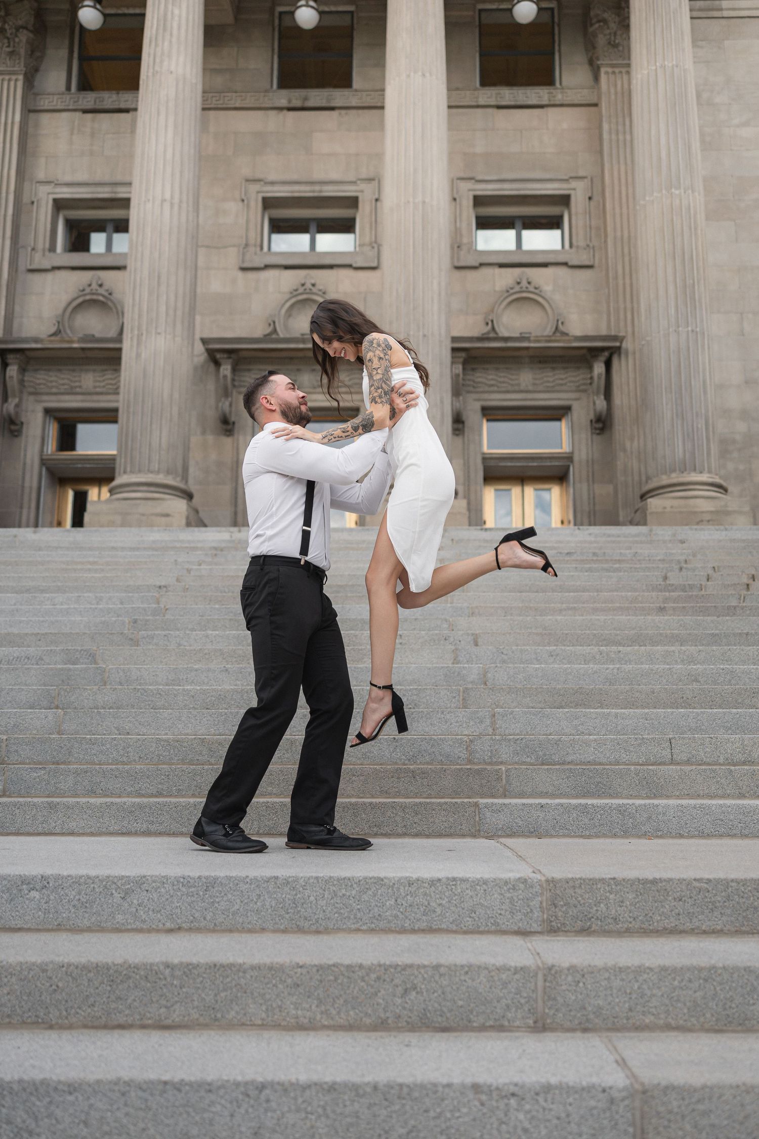 A dramatic dance dip pose performed on wide stone steps of a historic building.