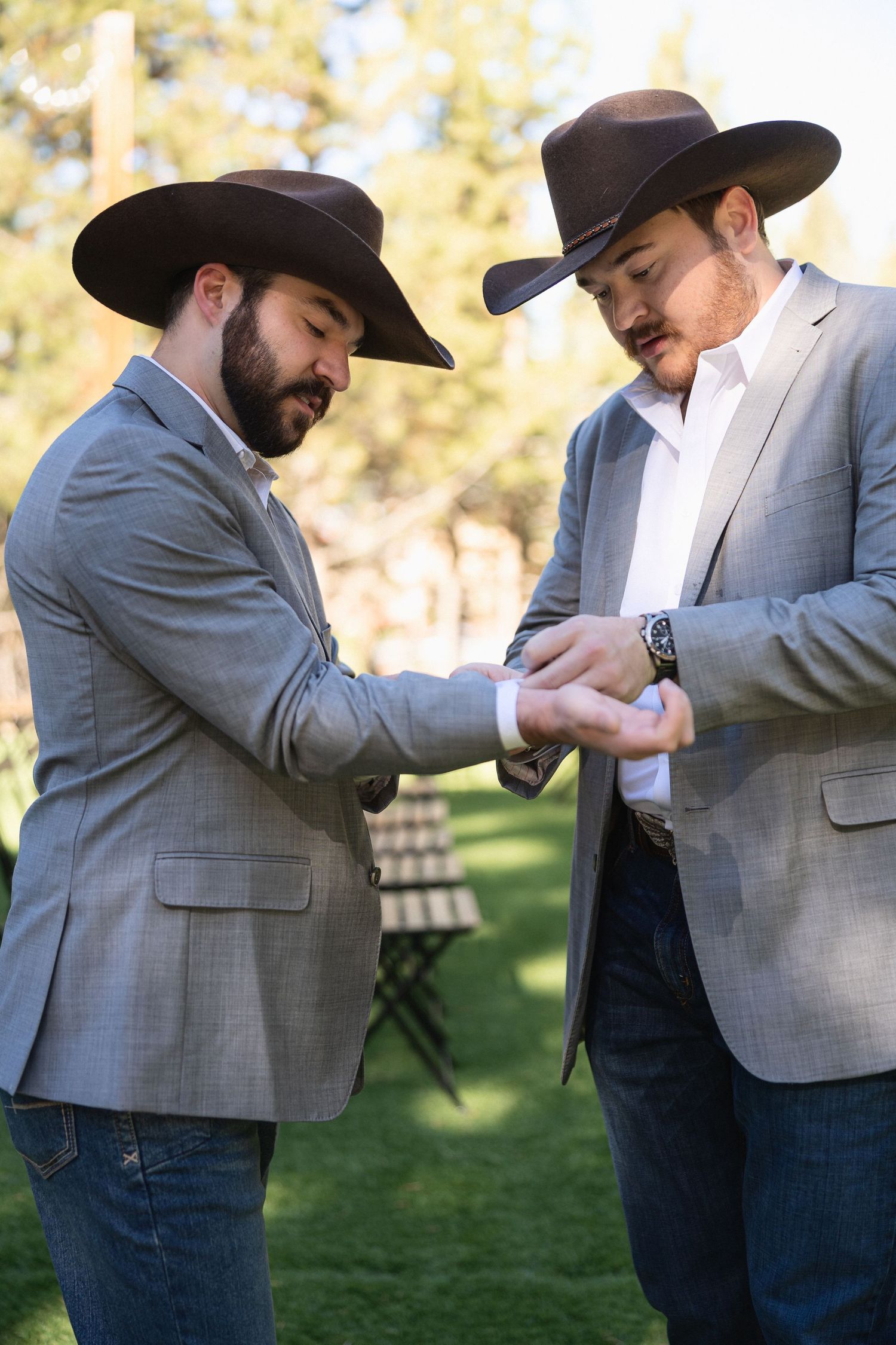 Two people in western attire and suits greeting each other with a playful handshake outdoors.