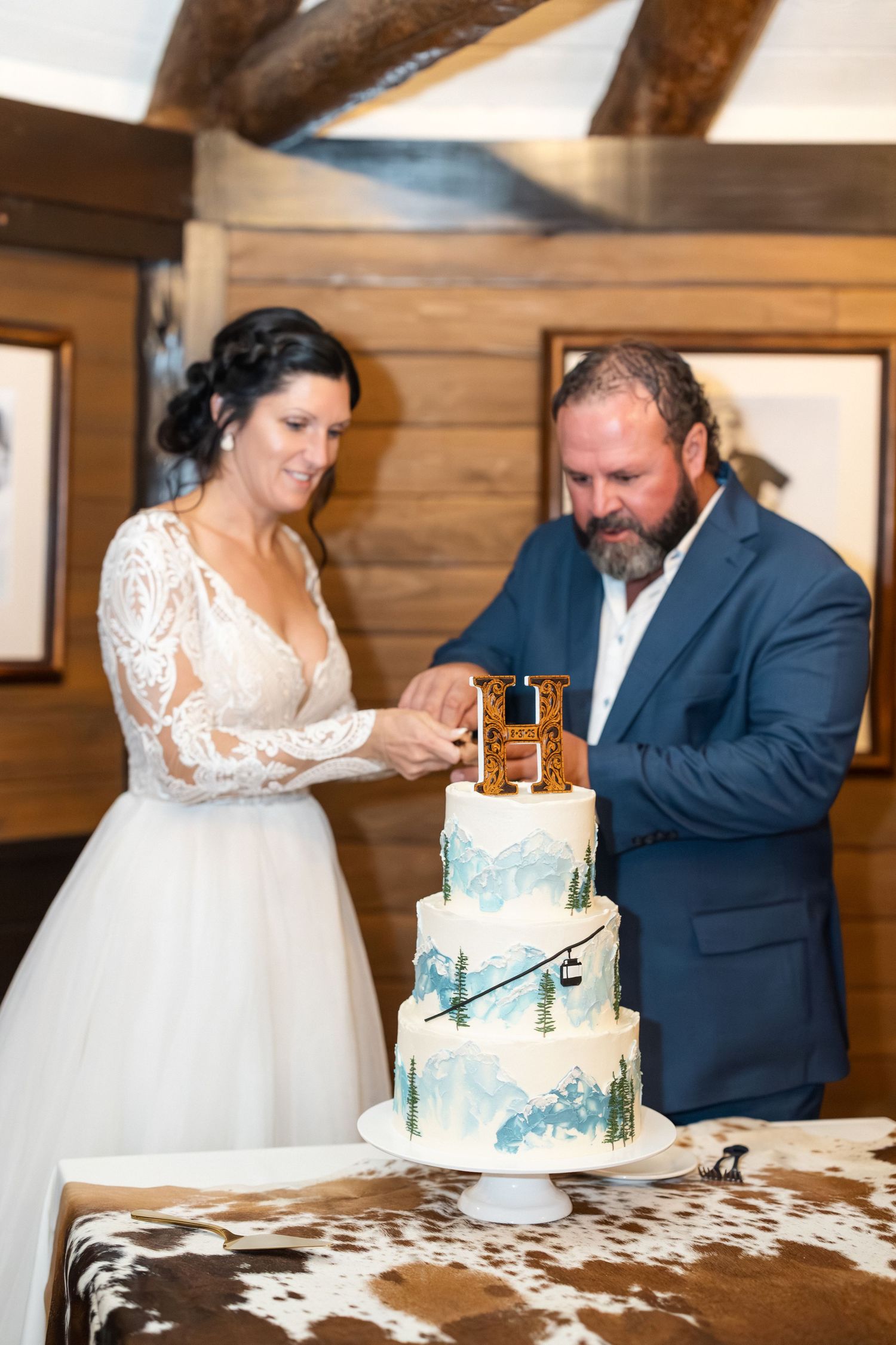 A couple shares their first bite of wedding cake in a rustic wooden venue.
