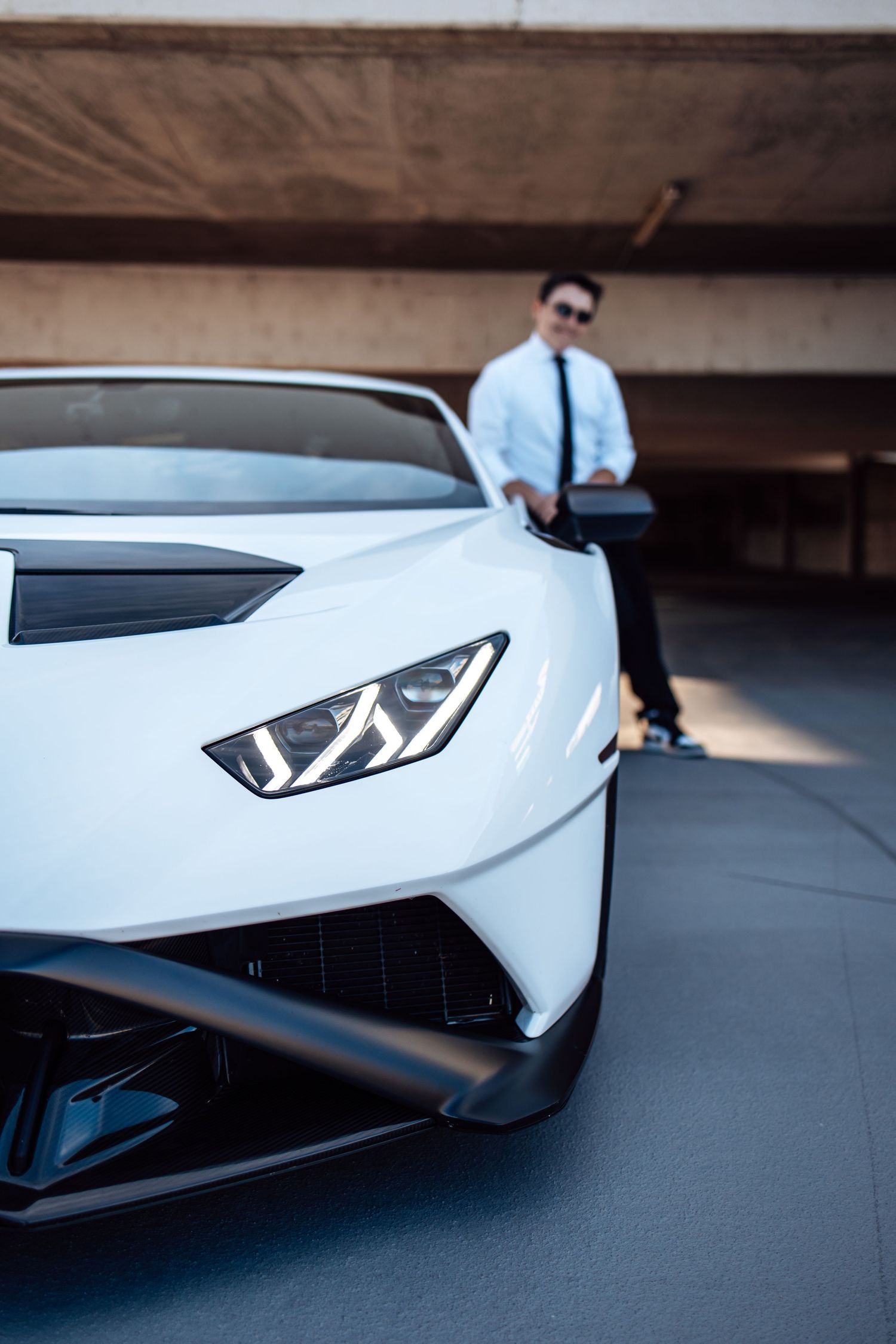 Close-up shots of a white Lamborghini supercar's angular front end details in a parking garage.