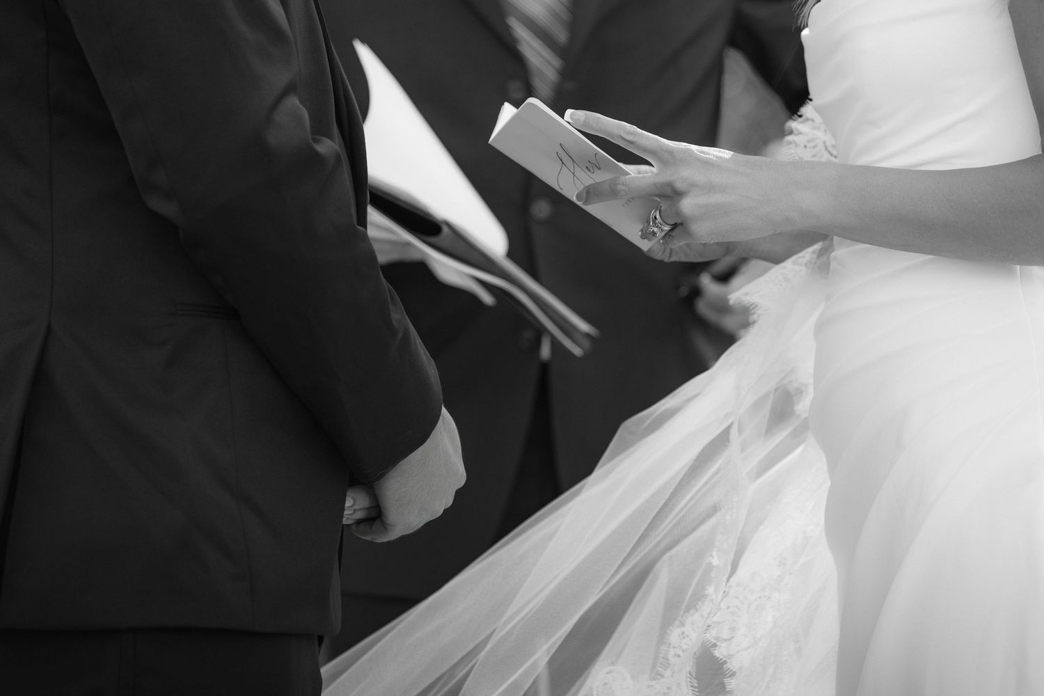 Black and white close-up of couple exchanging vows during wedding ceremony.