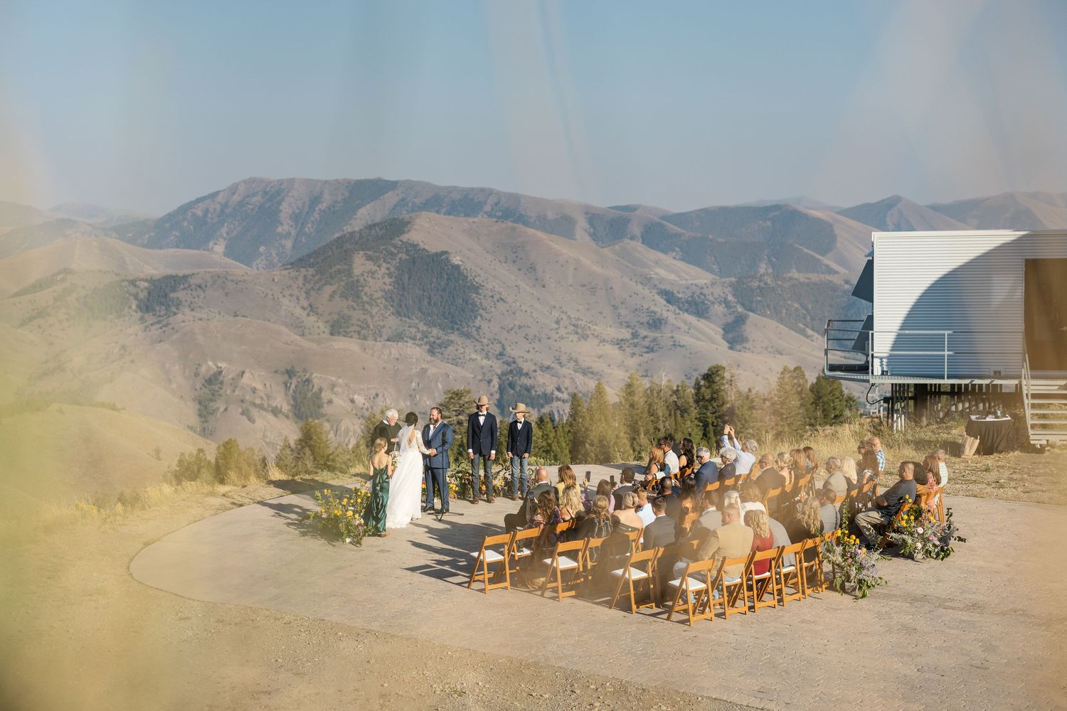 A soft-focus shot of a wedding ceremony taking place on a mountain overlook with dramatic views.
