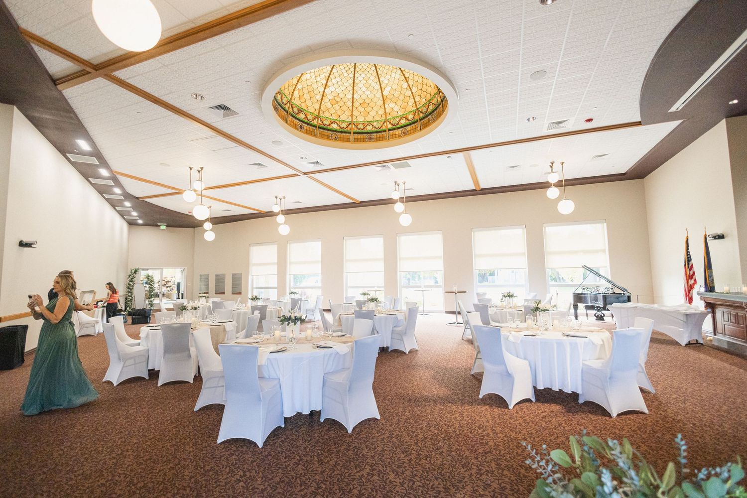 Elegant wedding reception hall with white-clothed tables and a golden domed ceiling.